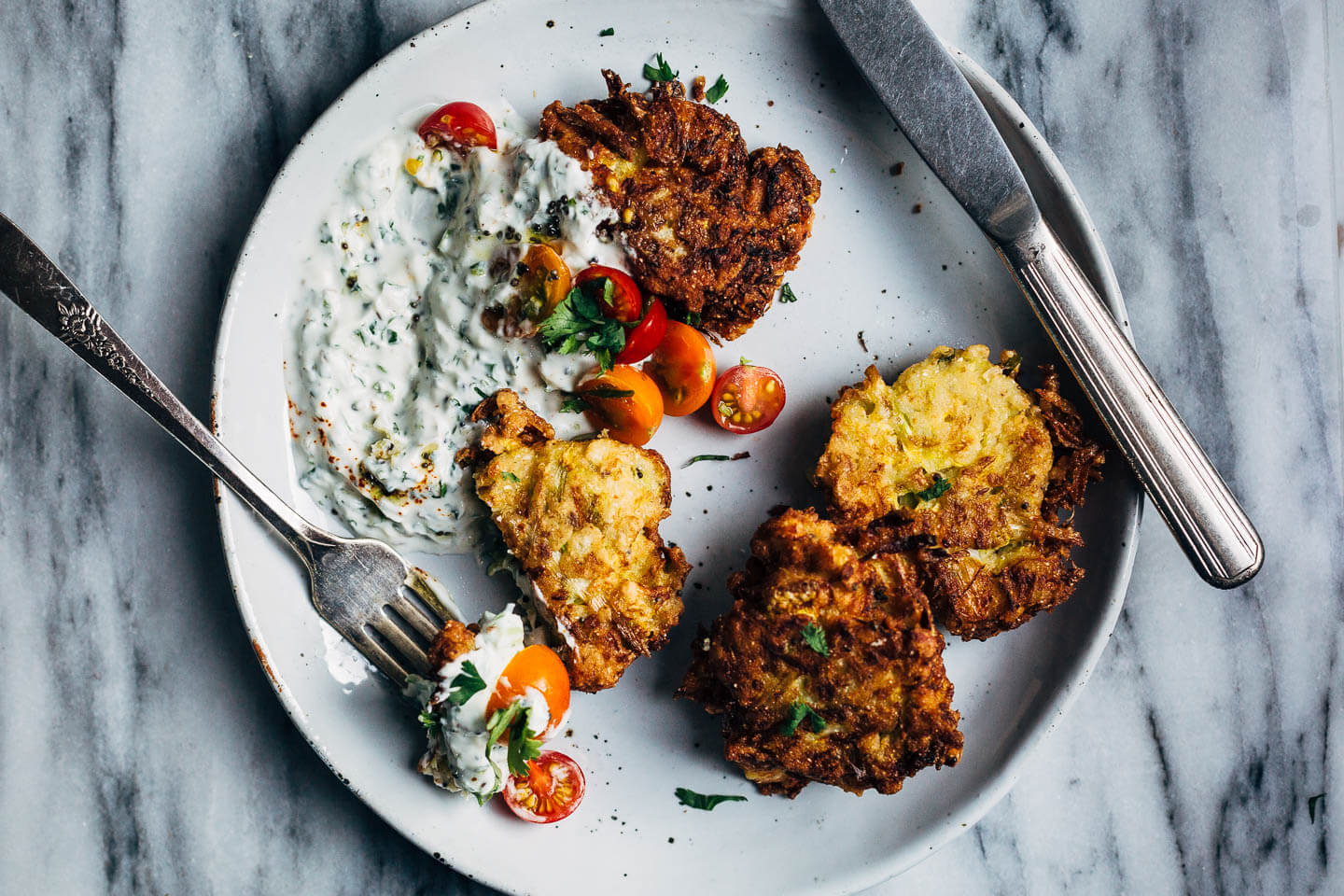 A plate of fritters with a forkful of food. 