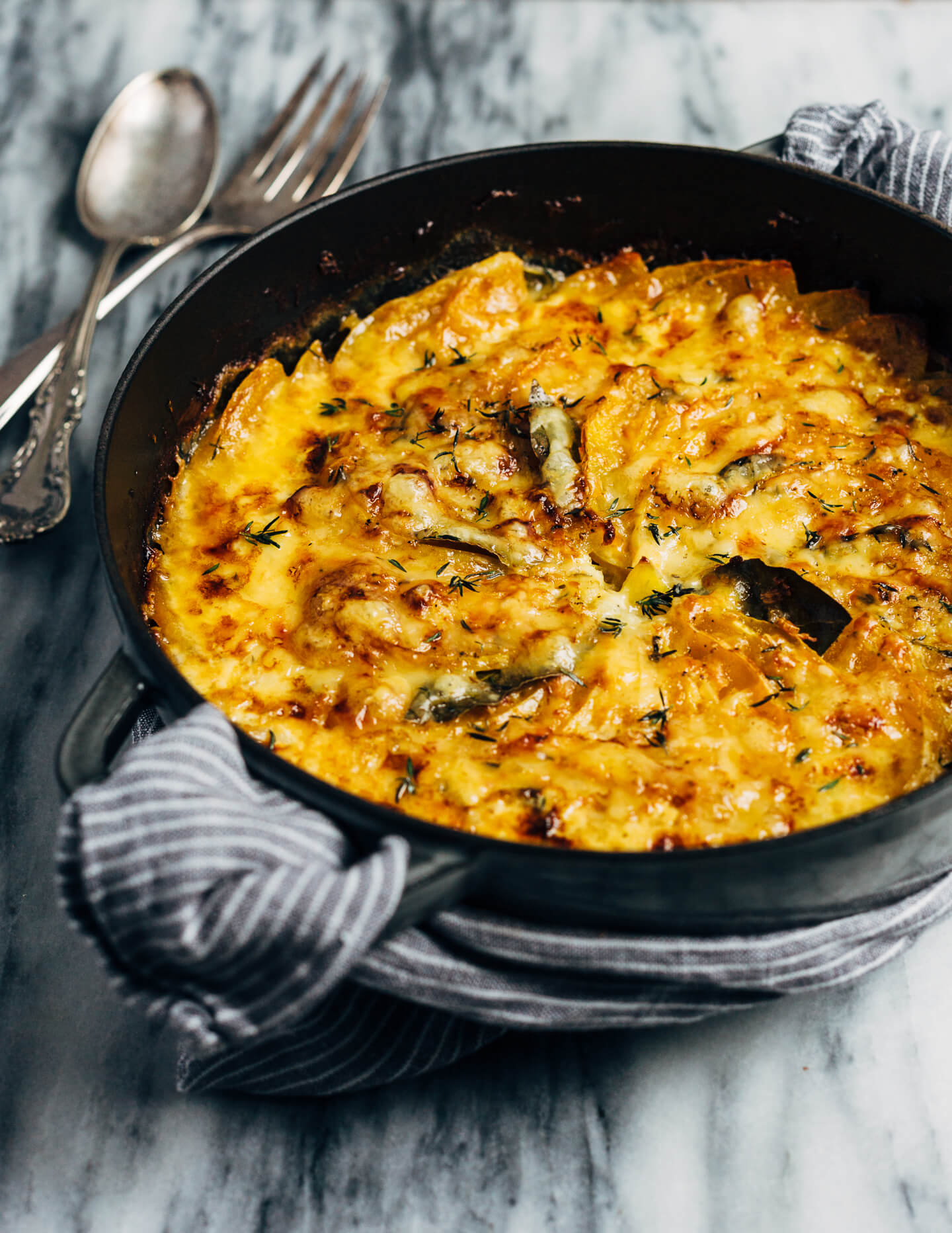 An autumnal butternut squash gratin made with a mix of Emmentaler and Gruyere cheeses, fresh thyme, and bay leaves. This hearty gratin is perfect as part of a cozy fall supper or as a Thanksgiving side.
