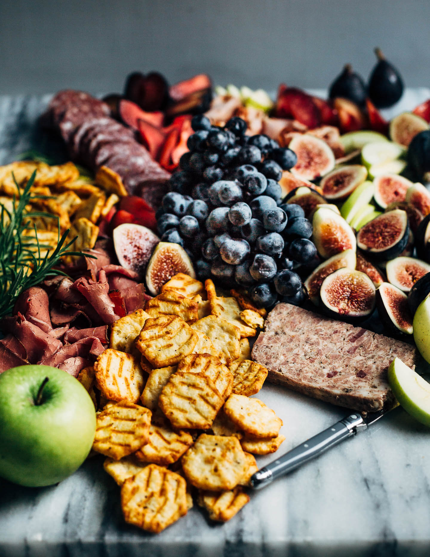 A creative charcuterie graze board that doubles as an eye-catching centerpiece for autumn gatherings. Featuring an assortment of meats, fresh fall fruit, and cheese crisps this charcuterie graze board comes together in minutes.