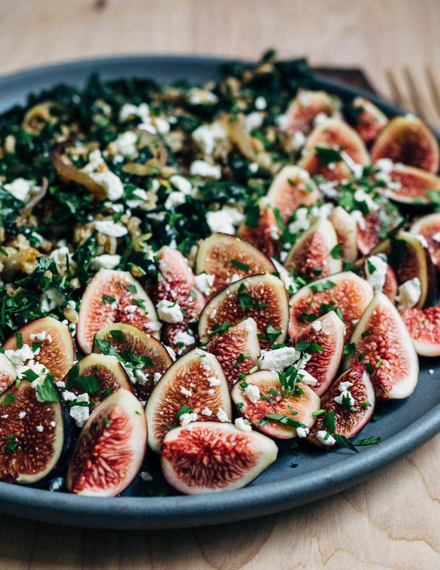 This nutty toasted farro salad features al dente farro tossed with massaged kale and ruby-hued fresh figs topped with creamy goat cheese crumbles and fresh parsley.