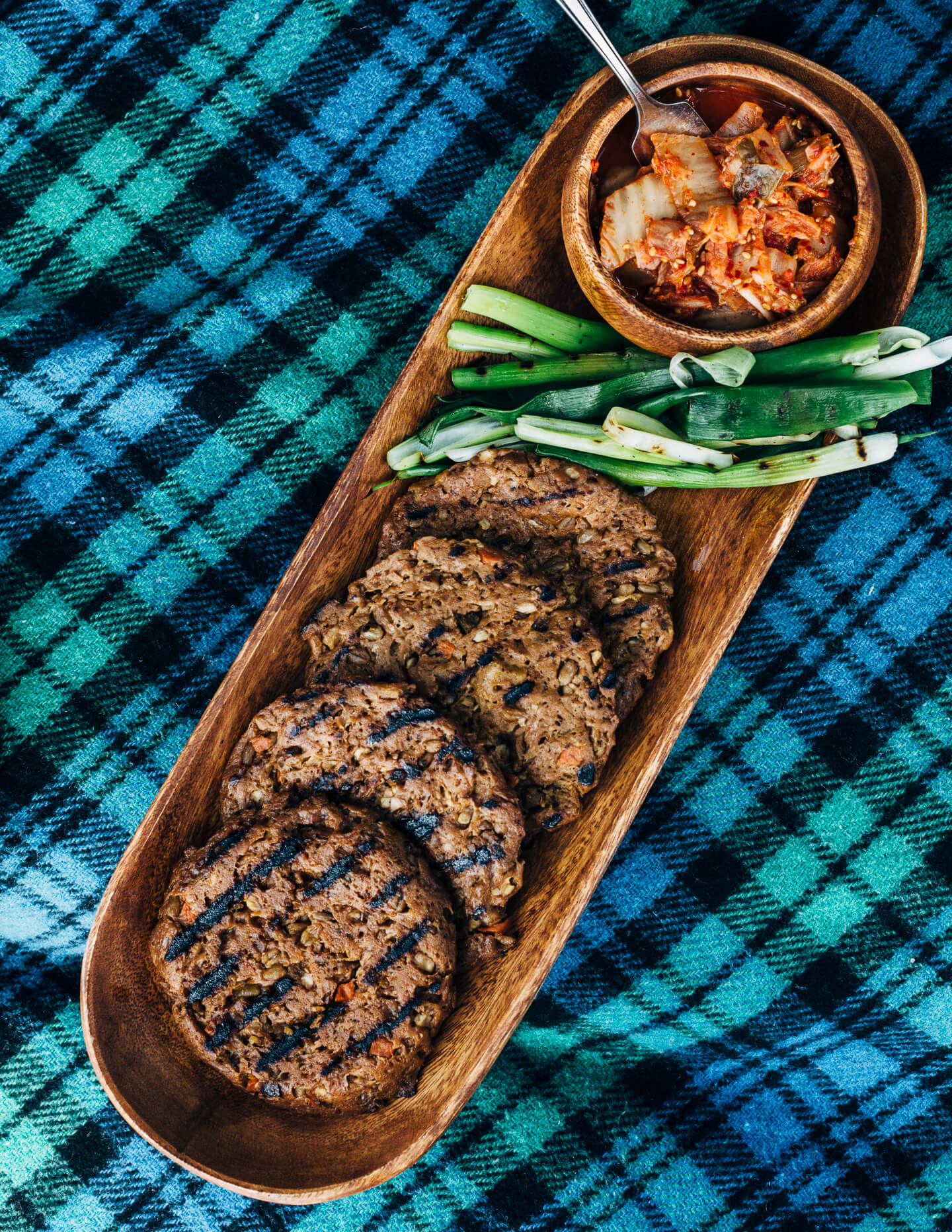 A fresh spin on the traditional tailgating party featuring plant-based kimchi burgers topped with grilled green onions and a spicy gochujang sunflower spread.