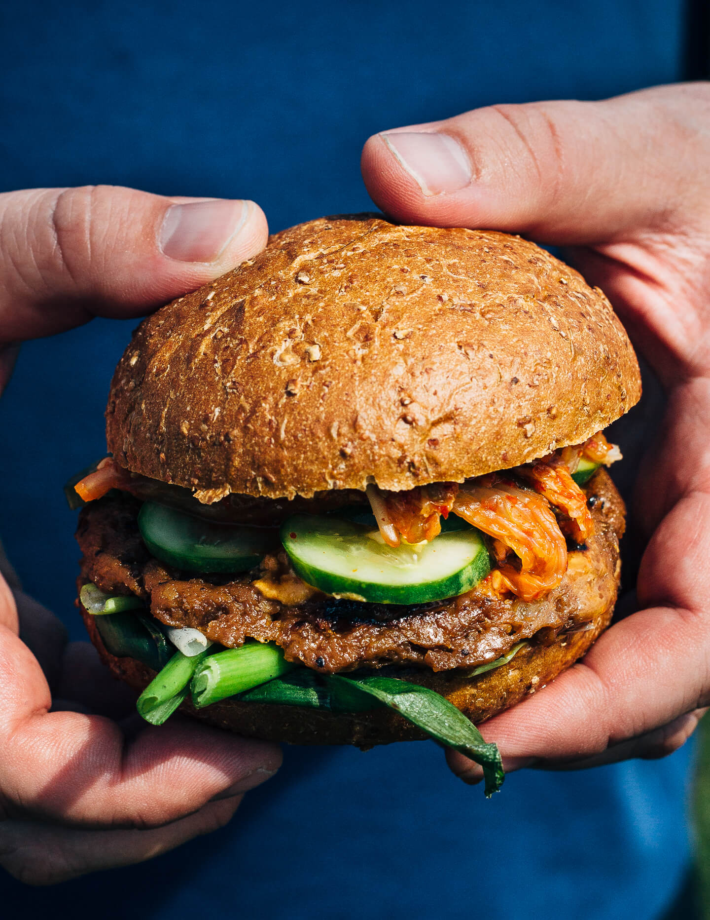 A fresh spin on the traditional tailgating party featuring plant-based kimchi burgers topped with grilled green onions and a spicy gochujang sunflower spread.