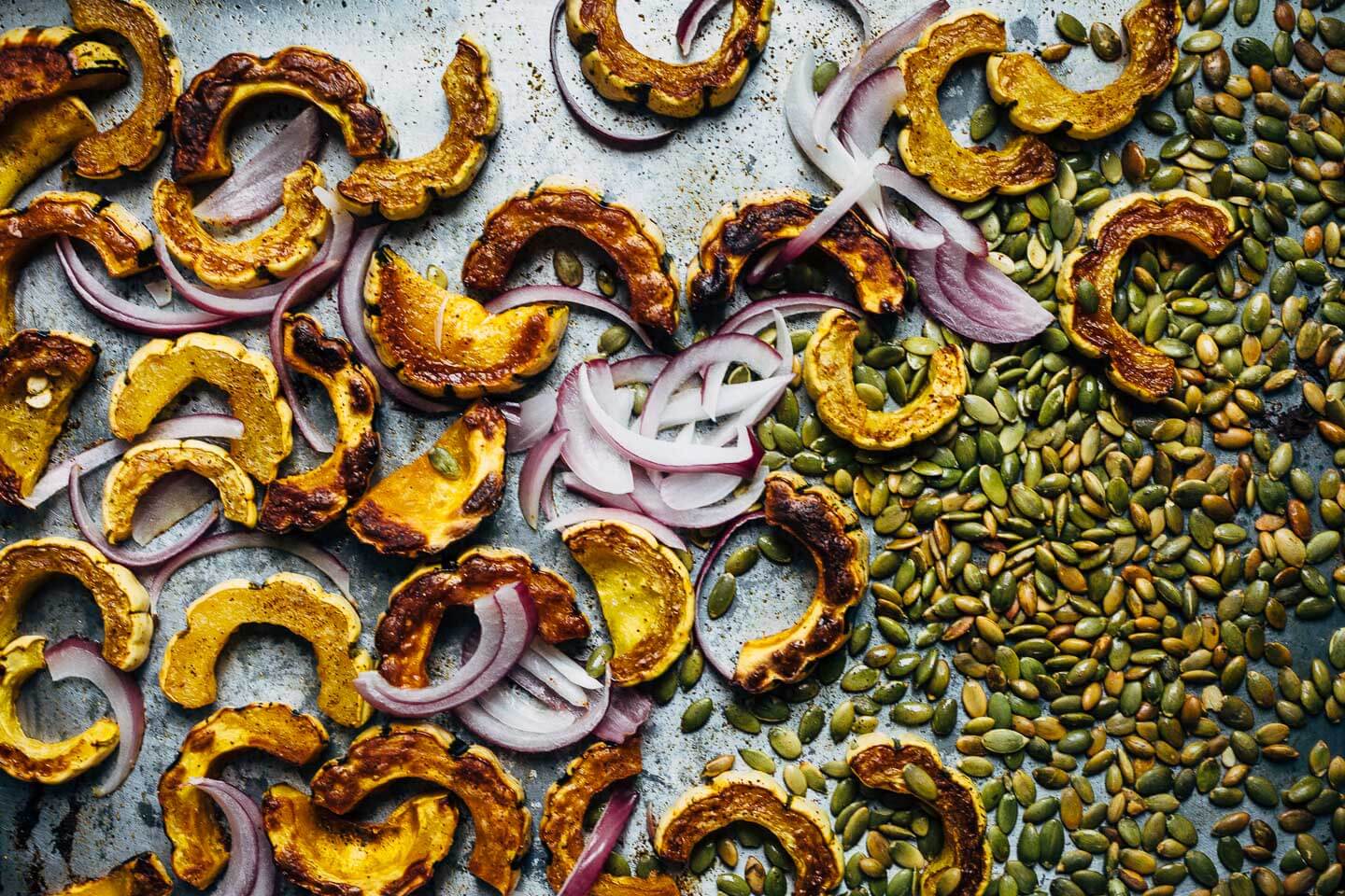 A vibrant, yet sturdy, pearl couscous and roasted delicata squash salad, tossed with tender kale, pomegranate arils, pepitas, and crumbled goat cheese, that's perfect as autumnal side dish or a versatile meal prep lunch. 