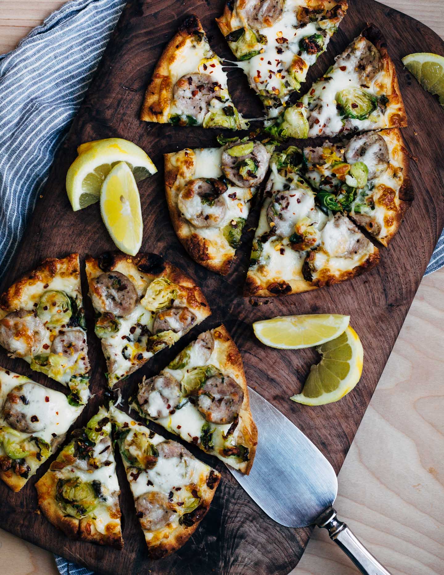 These sausage and Brussels sprout flatbread pizzas feature golden-edged roasted Brussels sprouts alongside tender sausage and melty mozzarella. Lemon zest and red pepper flakes punctuate the pizzas with brightness and heat, and lend a delightful complexity to this weeknight-friendly dish.