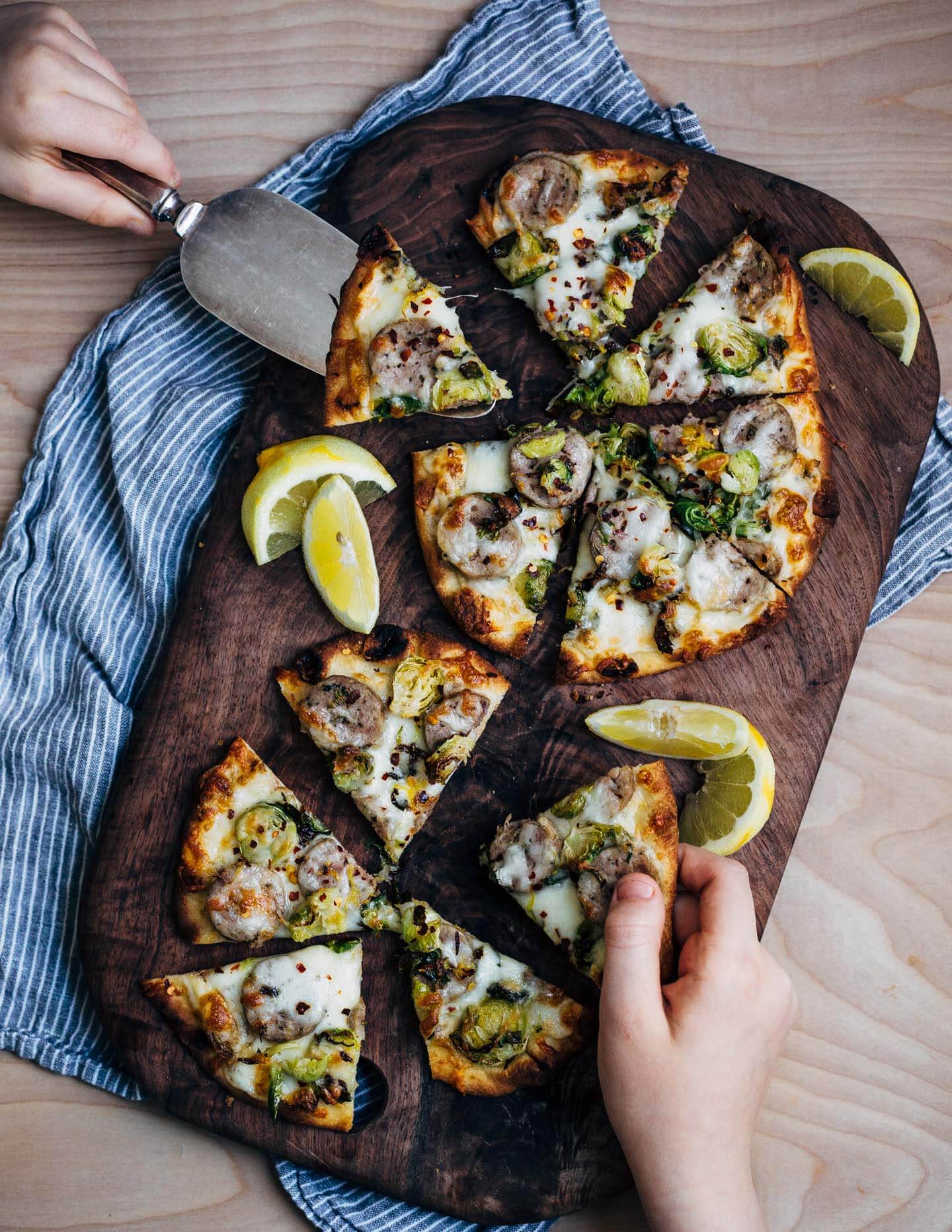 These sausage and Brussels sprout flatbread pizzas feature golden-edged roasted Brussels sprouts alongside tender sausage and melty mozzarella. Lemon zest and red pepper flakes punctuate the pizzas with brightness and heat, and lend a delightful complexity to this weeknight-friendly dish.