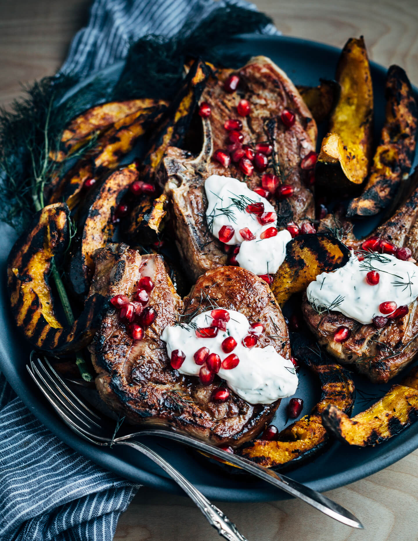 Add a pop of char and smoke to your Thanksgiving feast with this recipe for cumin-rubbed grilled lamb chops, grilled acorn squash wedges, dill and fennel tzatziki, and pomegranate arils. 