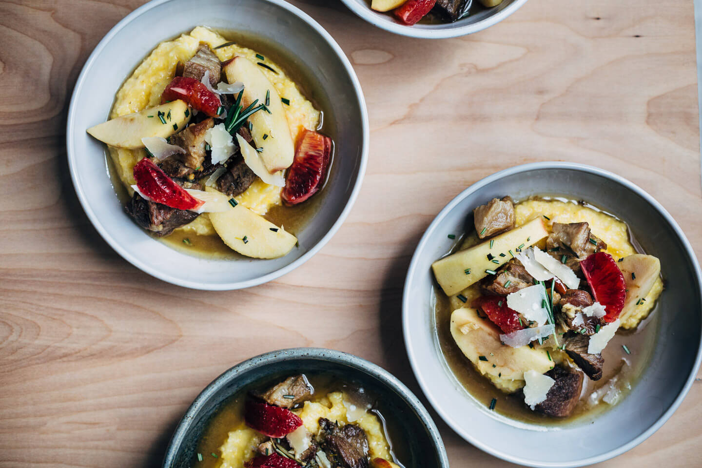 A simple and savory wintry stew featuring braised pork with apples, rosemary, chilies, and citrus served over polenta. 