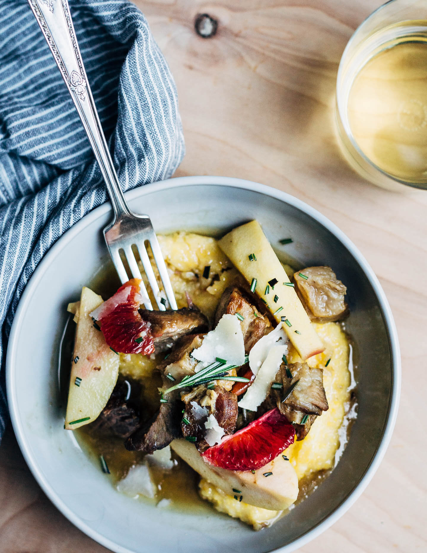 A simple and savory wintry stew featuring braised pork with apples, rosemary, chilies, and citrus served over polenta. 