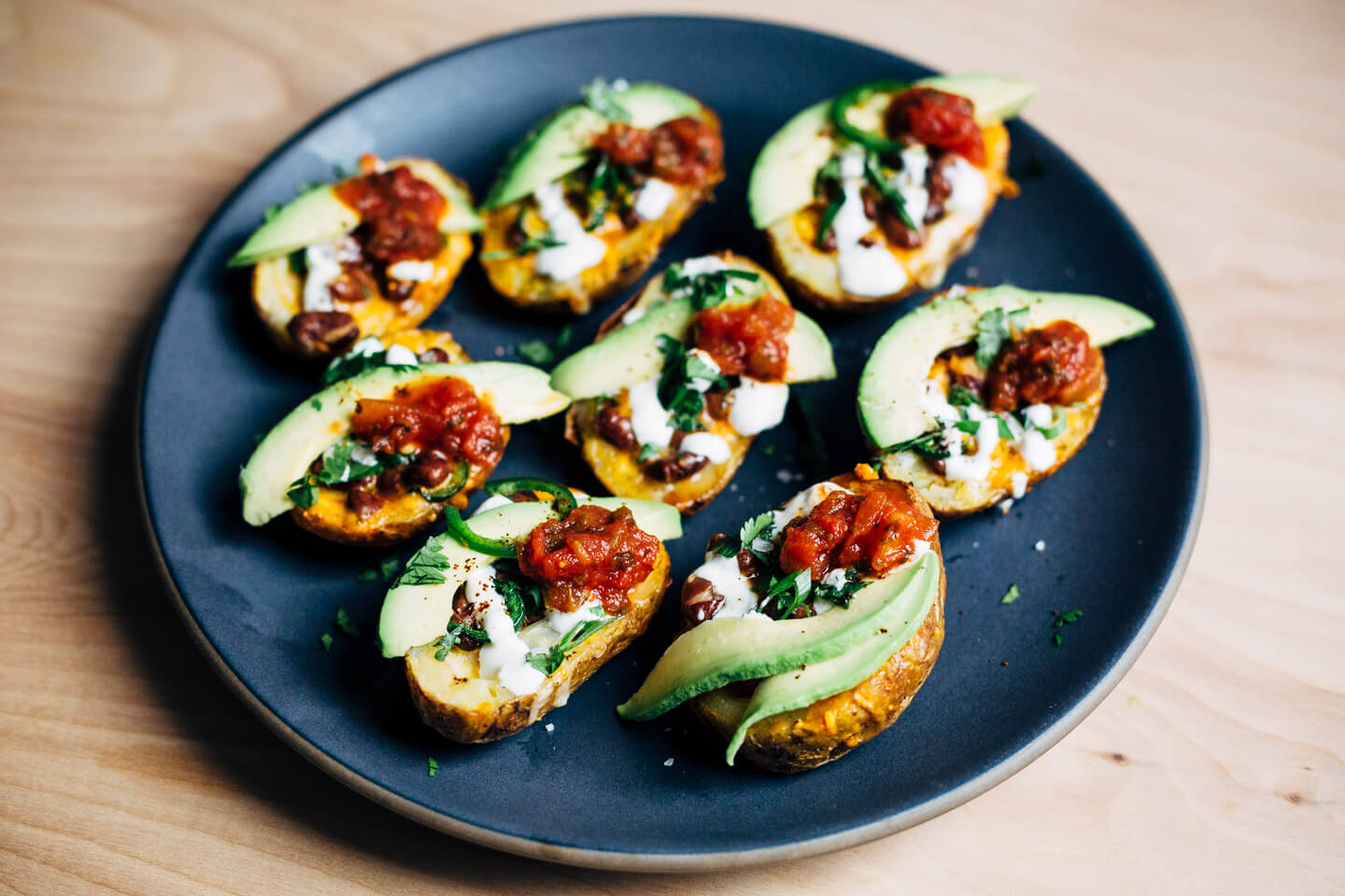 These vegetarian Tex-Mex potato skins are loaded with pinto beans, cheddar, green onions, herbs, jalapeños, avocado, and lime crema.