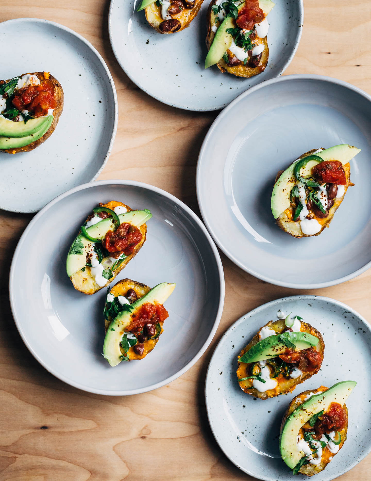 These vegetarian Tex-Mex potato skins are loaded with pinto beans, cheddar, green onions, herbs, jalapeños, avocado, and lime crema.