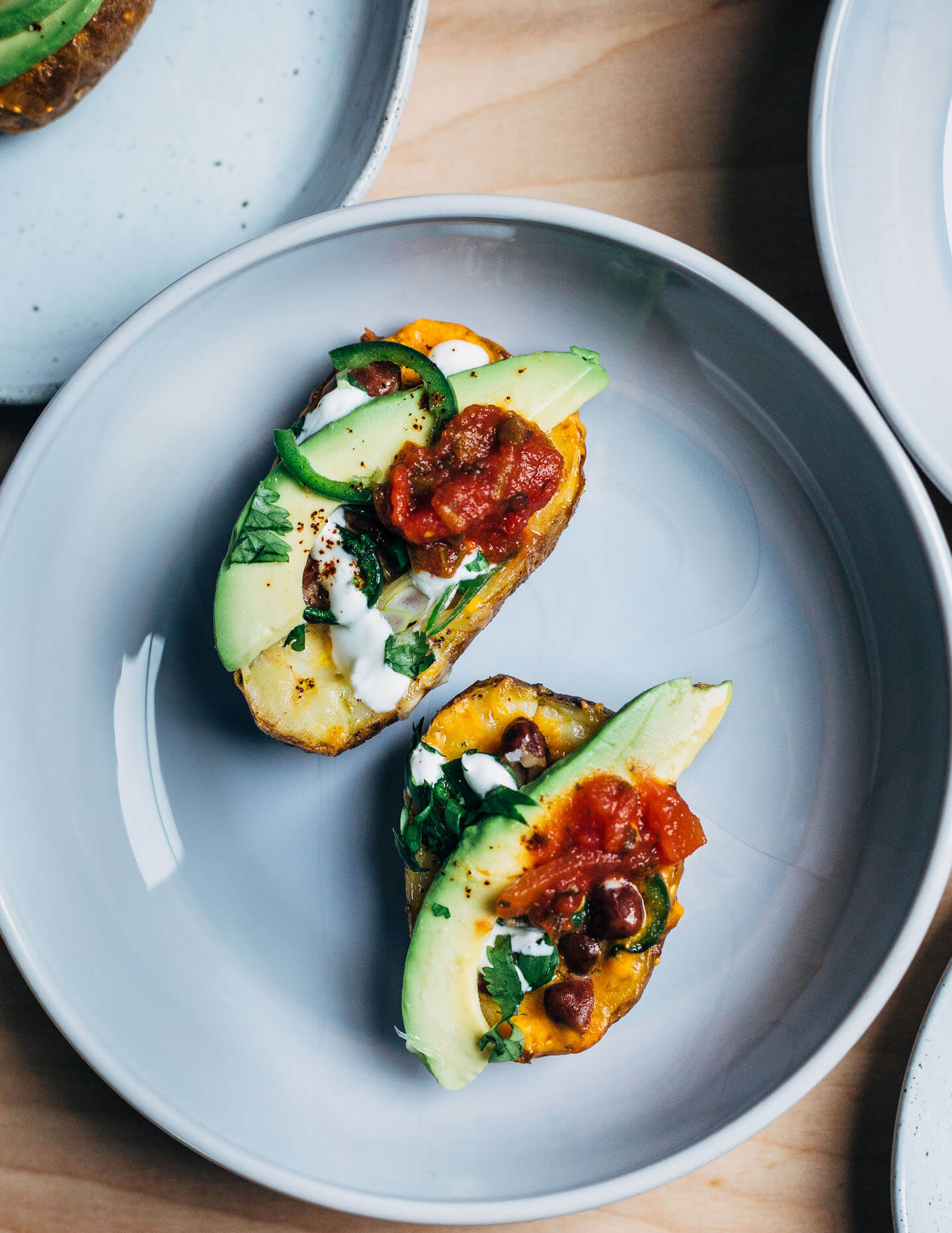 These vegetarian Tex-Mex potato skins are loaded with pinto beans, cheddar, green onions, herbs, jalapeños, avocado, and lime crema.