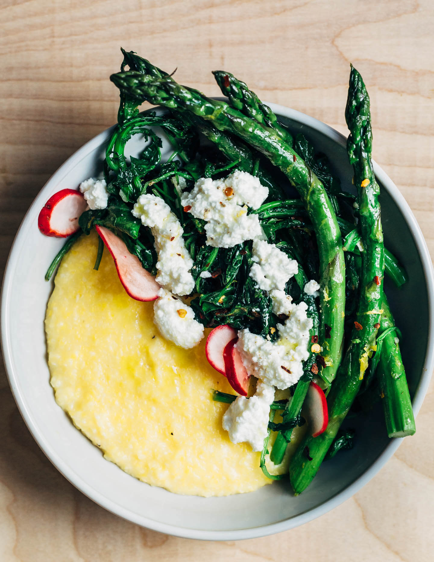 These versatile asparagus polenta bowls are a study in contrasting flavors and textures. Buttery polenta counters the bitter notes of spring greens and asparagus, while creamy ricotta tempers the heat of red pepper flakes and young garlic. 