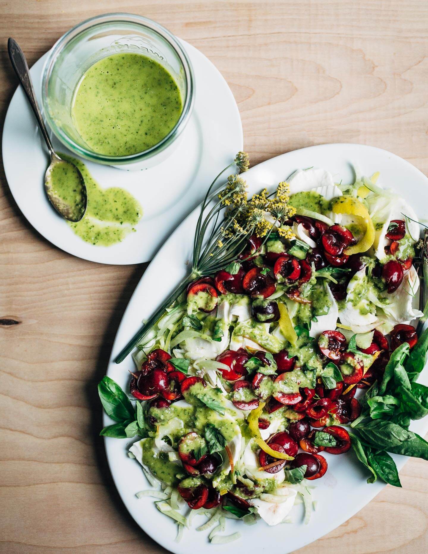 This shaved fennel and Bing cherry Caprese salad is layered with creamy mozzarella, and drizzled with an herbaceous basil and green onion dressing.