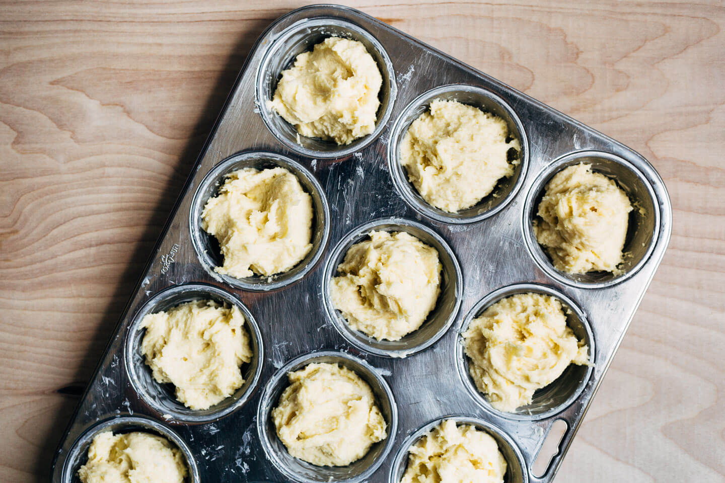 A muffin tin filled with semolina batter for shortcakes. 