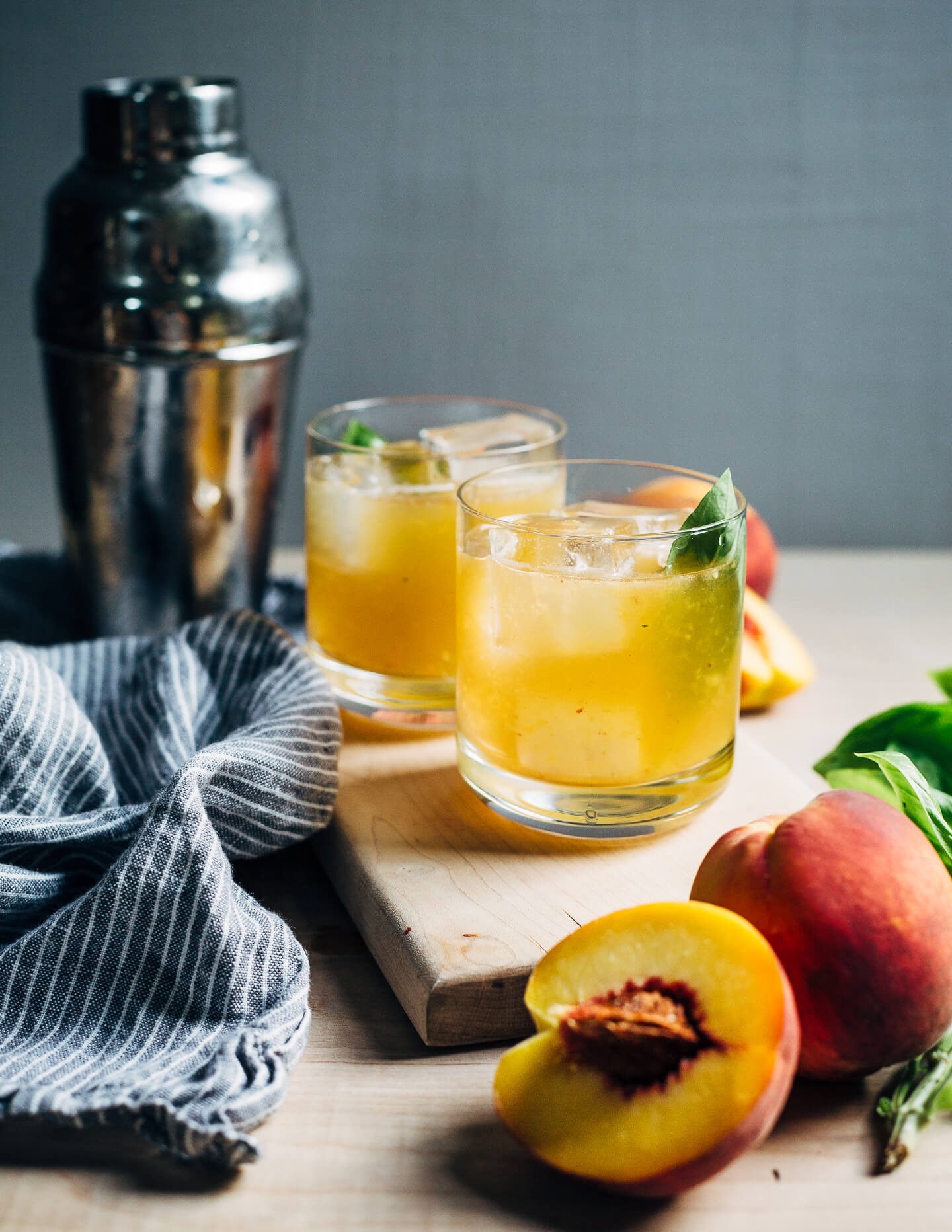 Peach bourbon smash cocktails infused with fresh basil leaves are bright, lemony, and the perfect way to enjoy sweet summer peaches. 