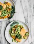 A quick and summery dinner recipe featuring savory zucchini noodles and cilantro pesto topped with broiled salmon. 