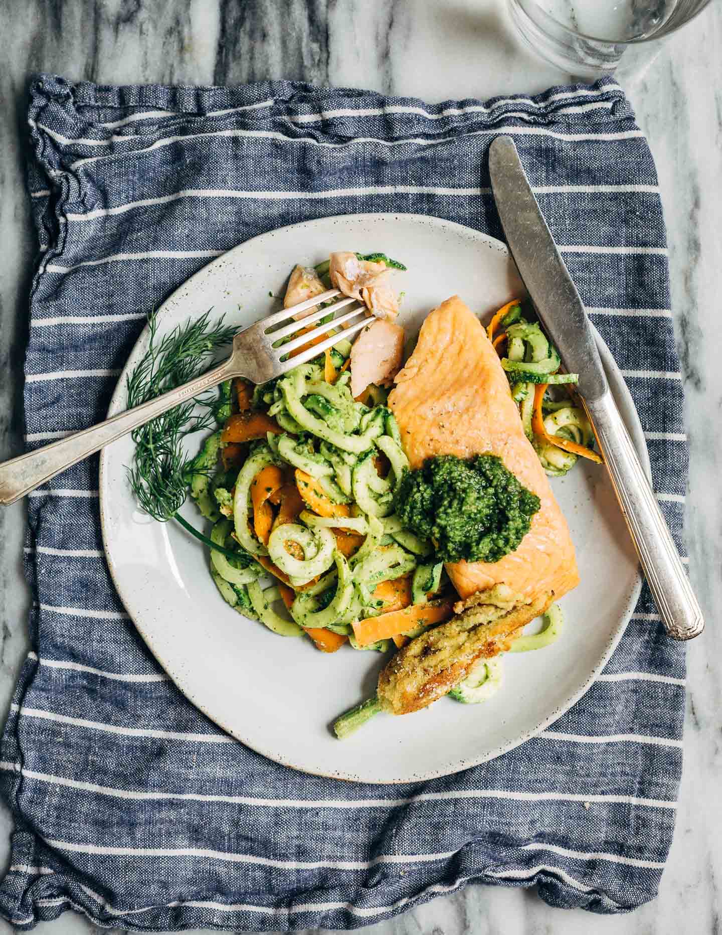 A quick and summery dinner recipe featuring savory zucchini noodles and cilantro pesto topped with broiled salmon. 