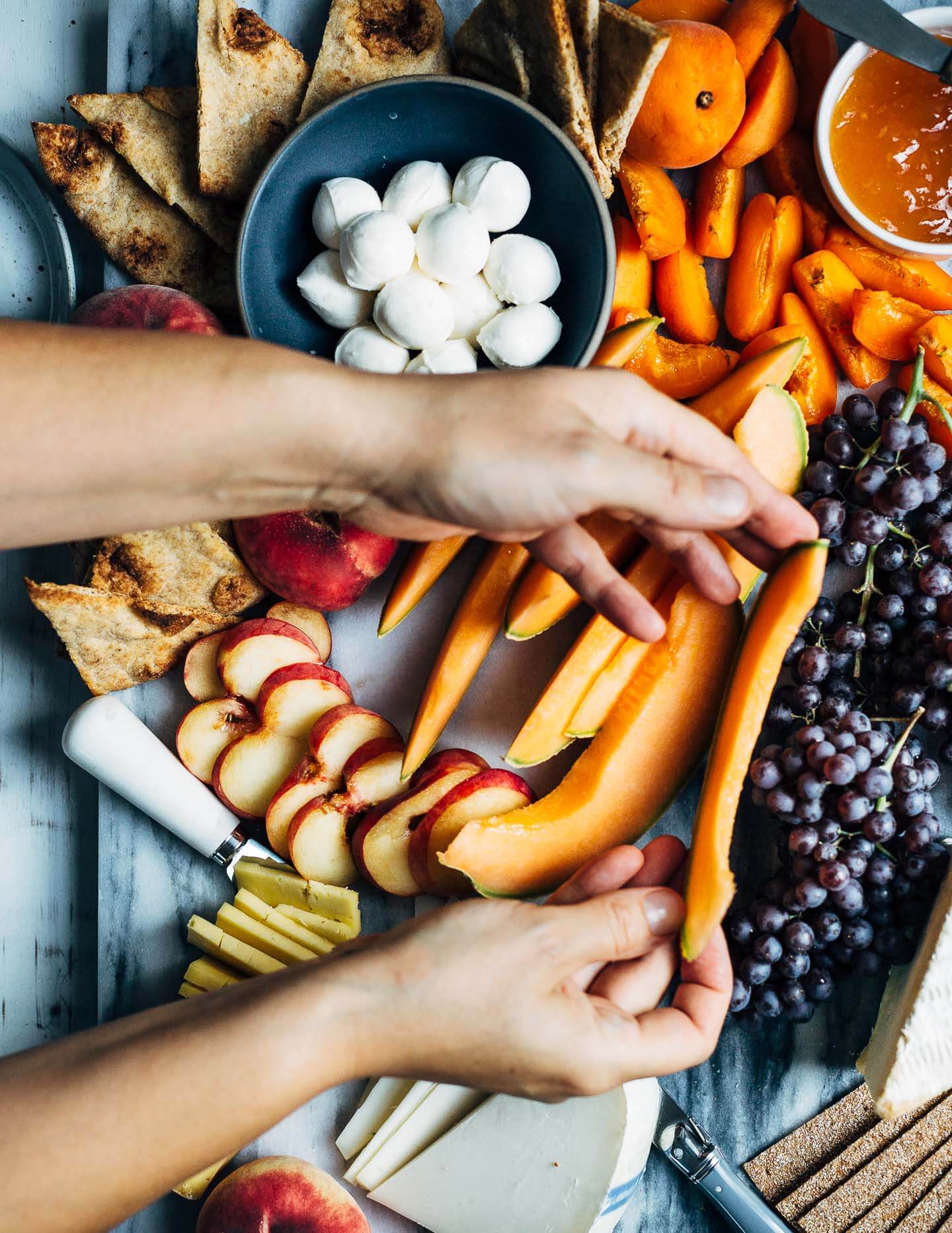 A summer fruit and cheese board featuring fresh cantaloupe wedges. 