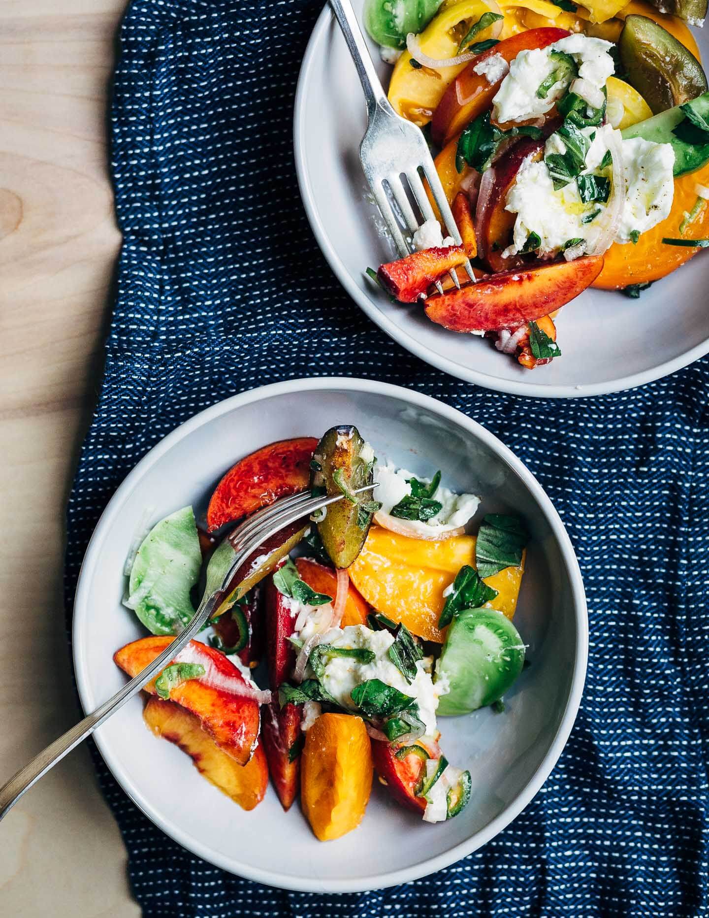 A summery stone fruit and tomato salad in two bowls. 