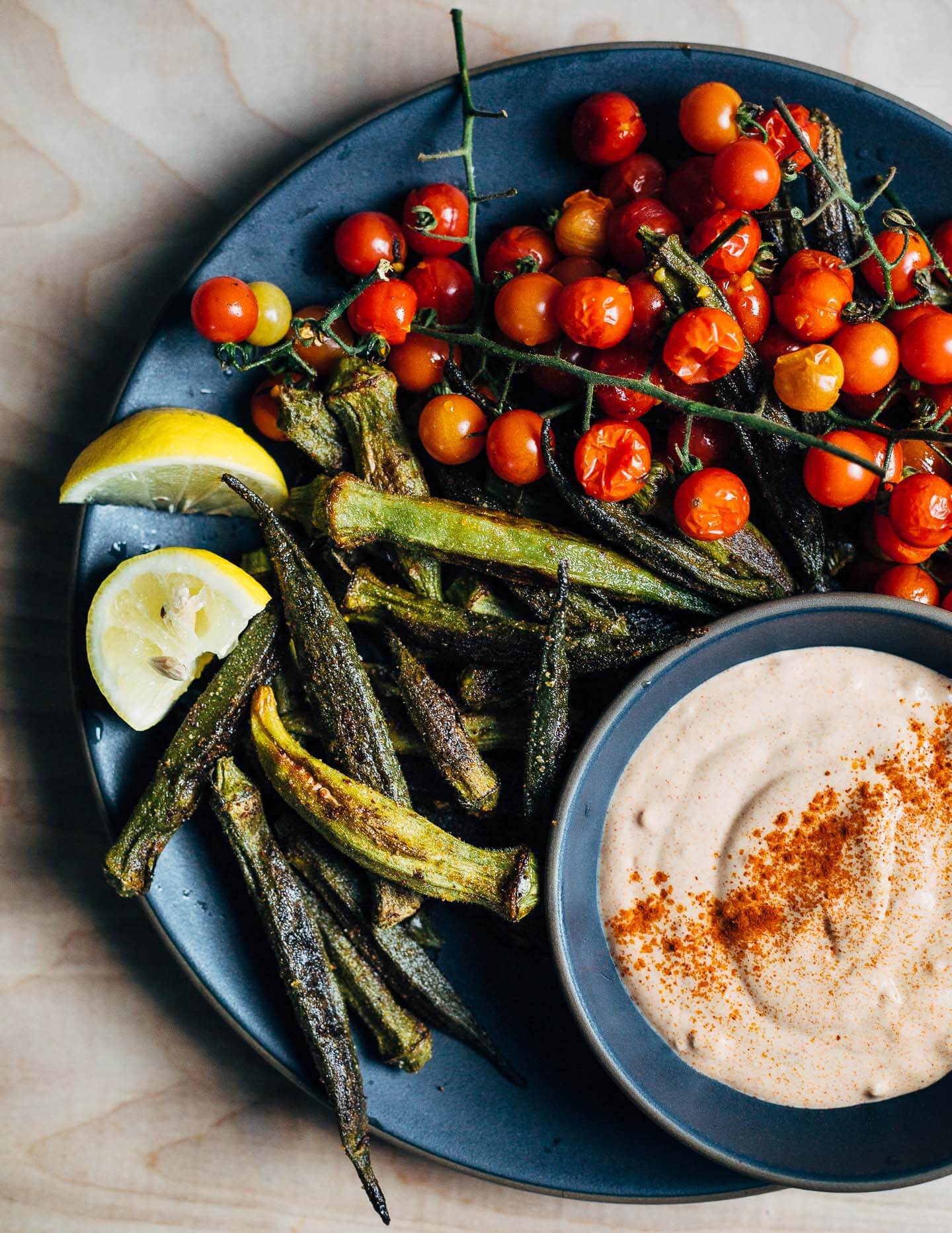 Perfect as a side or light summer meal, crispy roasted okra and cherry tomato bunches are served alongside an irresistible (cheater) pimentón aioli made with store bought mayo and smoked paprika. 