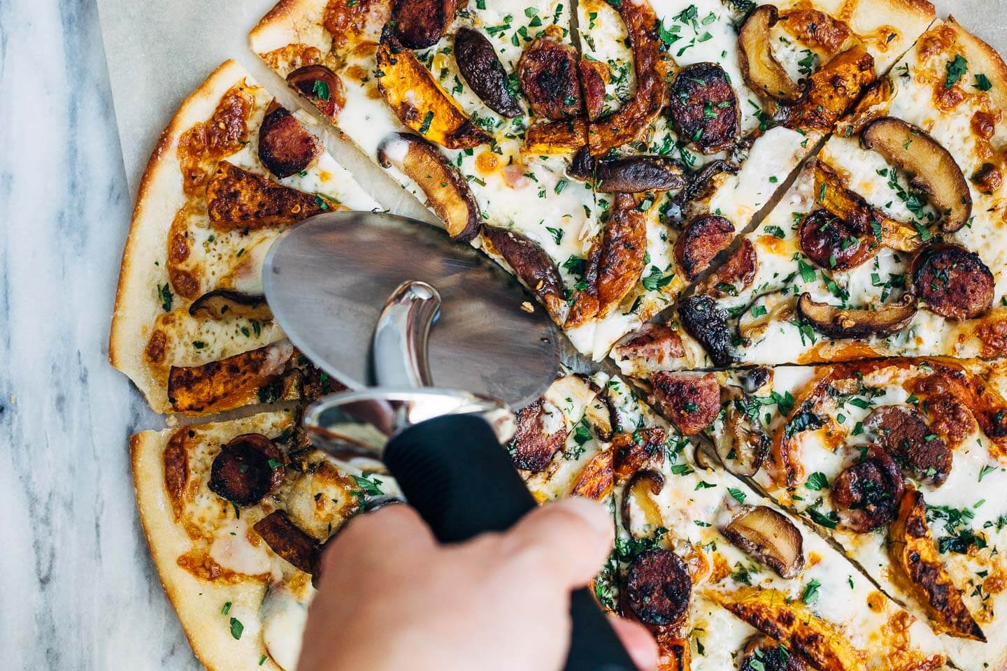 Cutting up a roasted butternut squash and sausage pizza. 