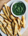 A platter with roasted potato wedges and zhug sauce