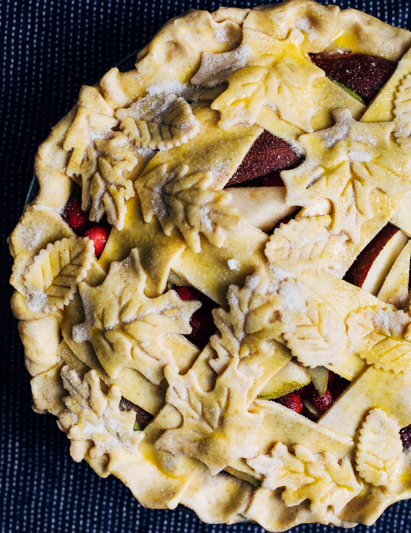 Cranberry pear pie with a decorative leaf crust, ready to bake. 