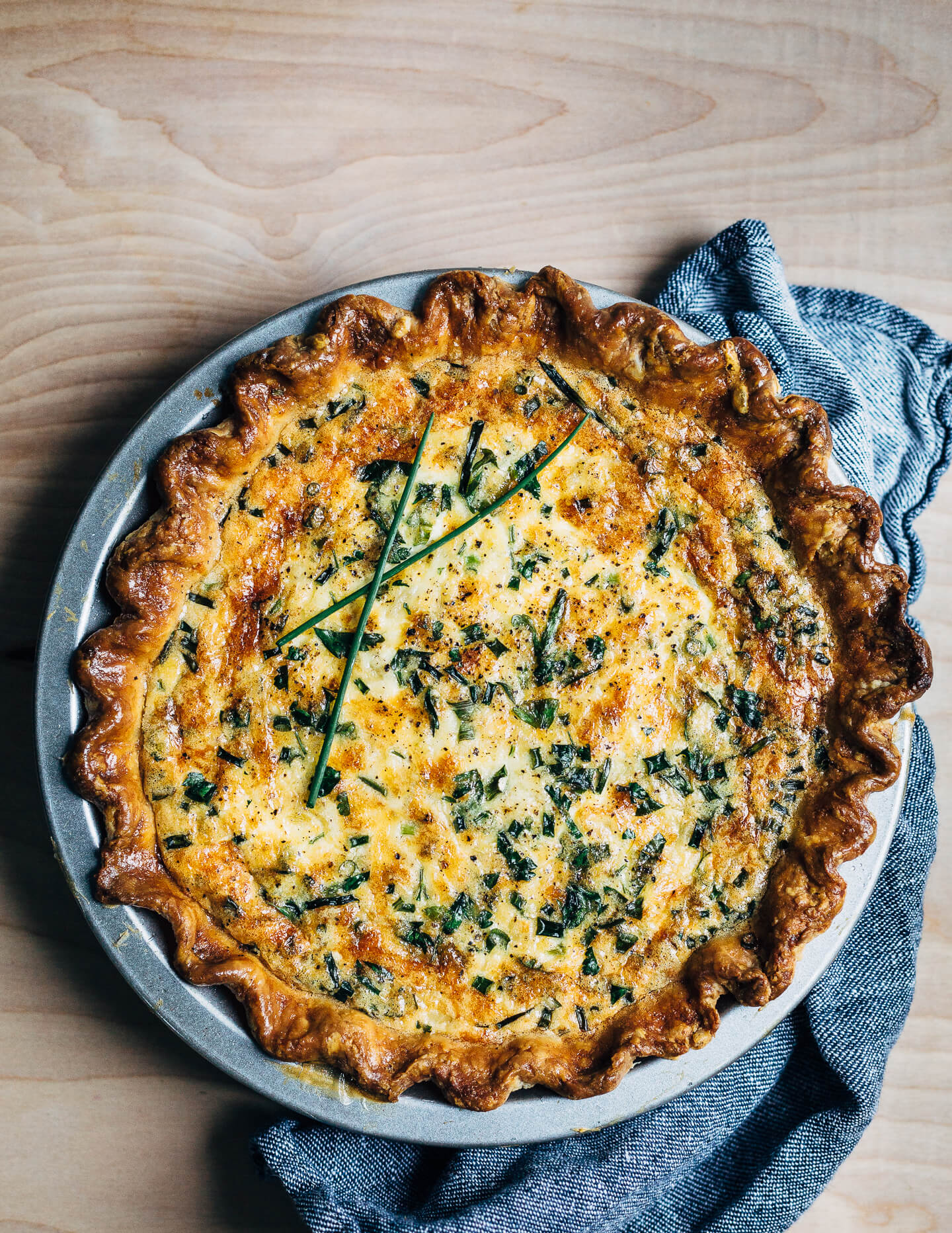A simple chive and cheddar quiche recipe that makes the most out of refrigerator staples like eggs, cheddar, and butter. Yellow onions caramelized in butter and whatever fresh herbs you can find lend flavor and contrast to this wonderfully rich vegetarian quiche. 
