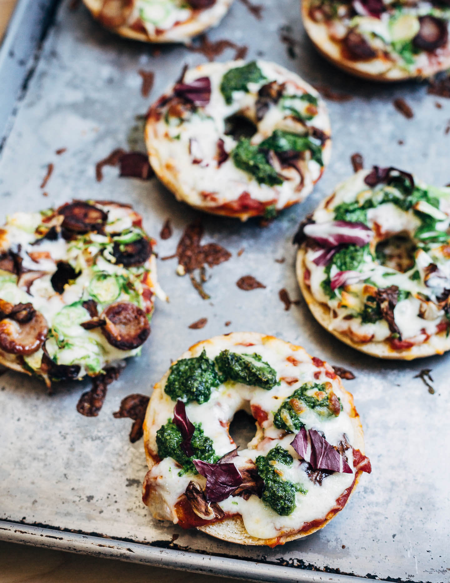 Pizza bagels with pesto, sausage, and spring vegetables, just out of the oven. 