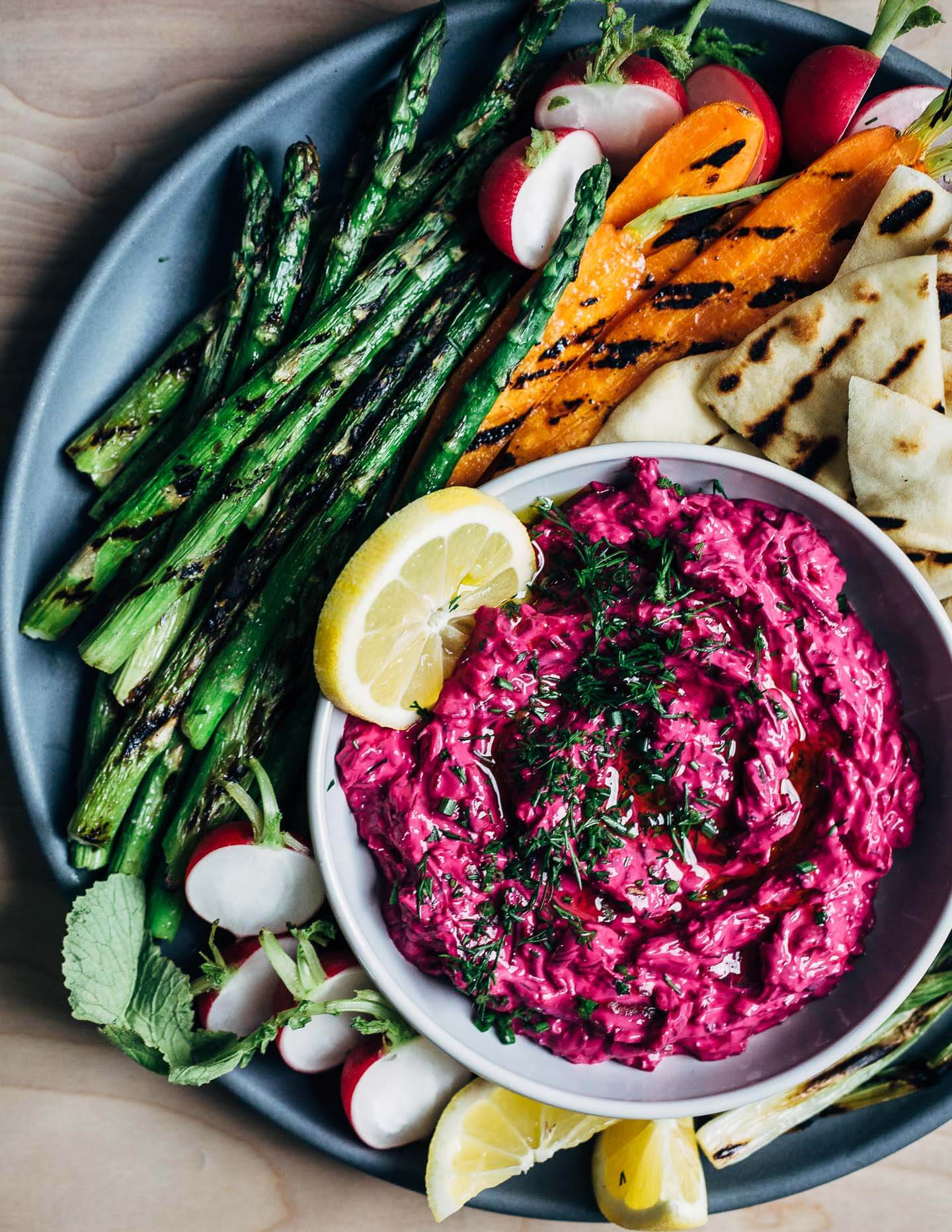 Super vibrant plant-based beet tzatziki served with grilled asparagus, spring carrots, and naan. 