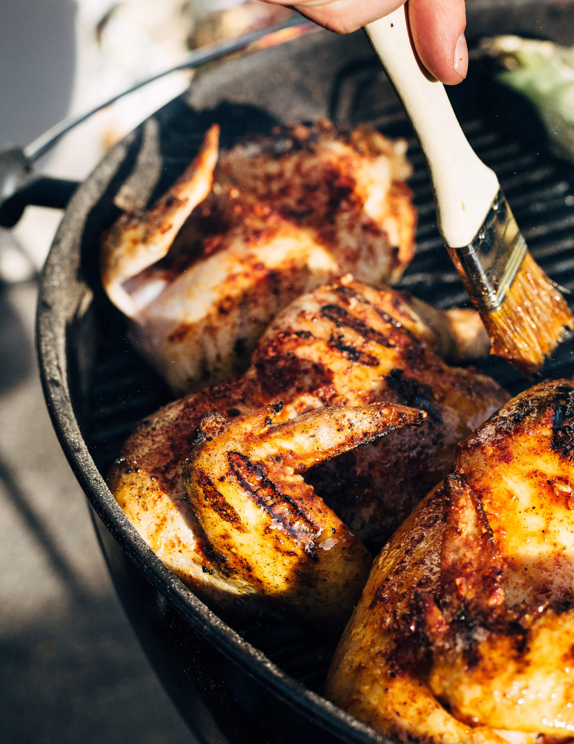 Brushing honey butter onto grilled whole chicken. 