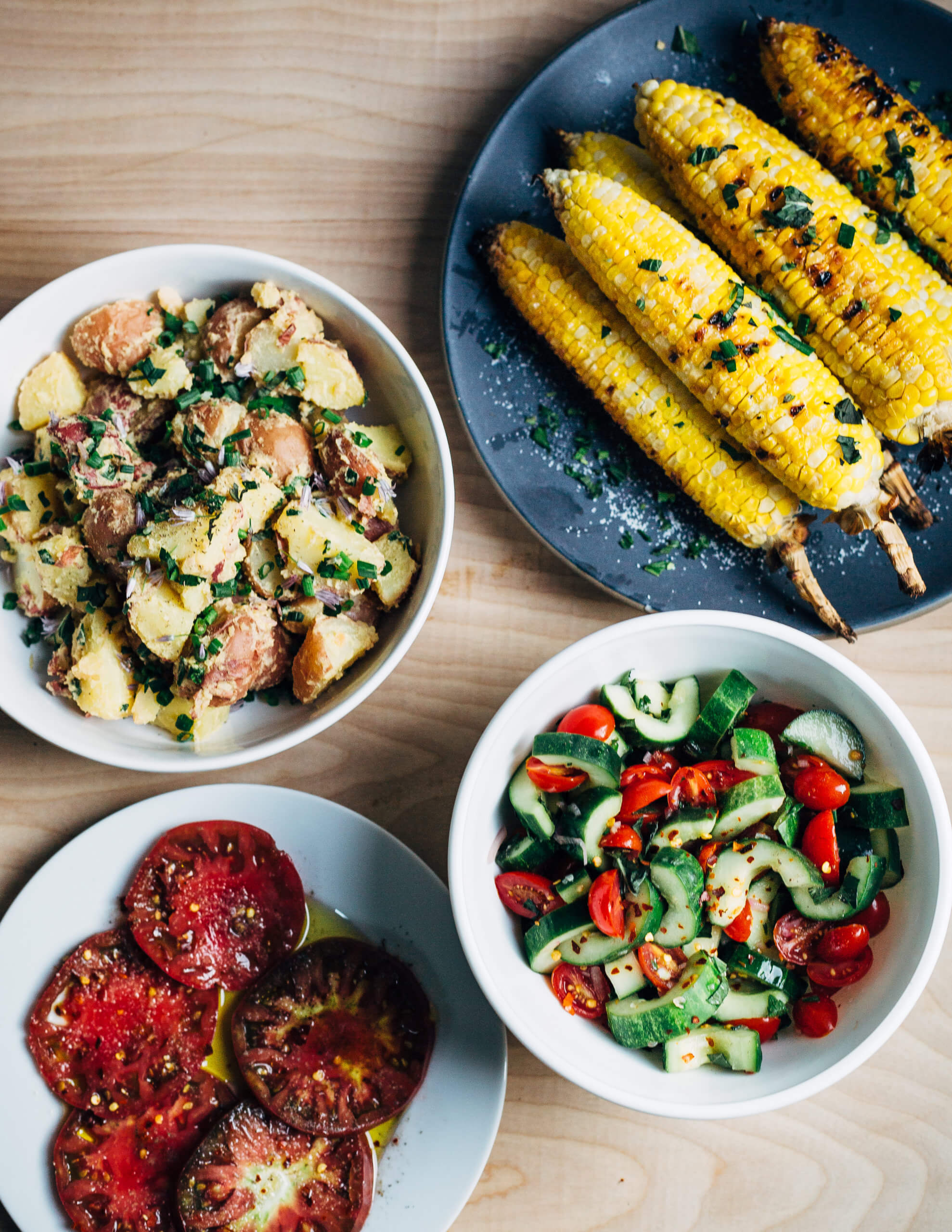 Simple sides for a cookout: grilled corn, cucumber and tomato salad, Dijon potato salad, and sliced tomatoes.