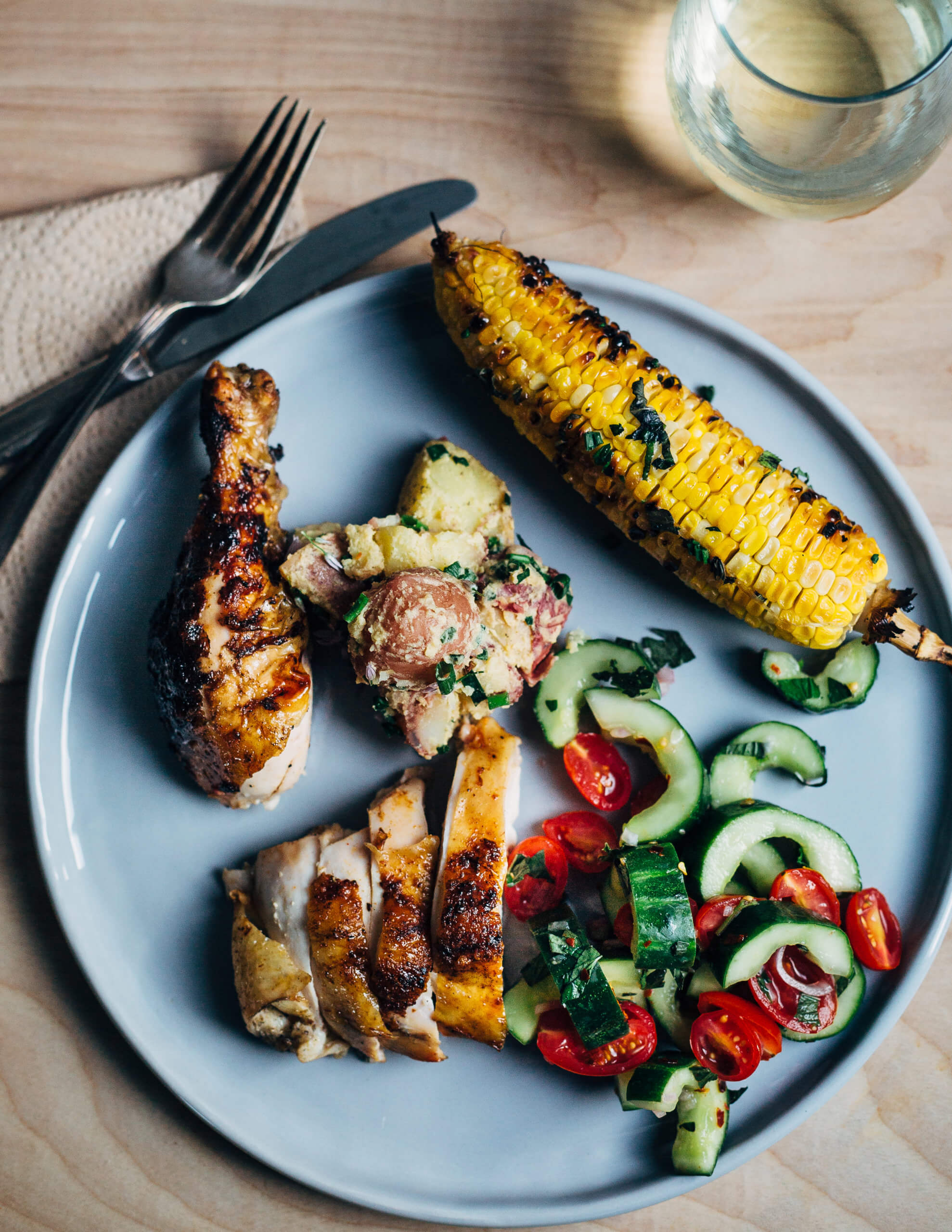 The perfect summer cookout plate: paprika and garlic grilled chicken, cucumber and tomato salad, Dijon potato salad, and corn on the cob. 