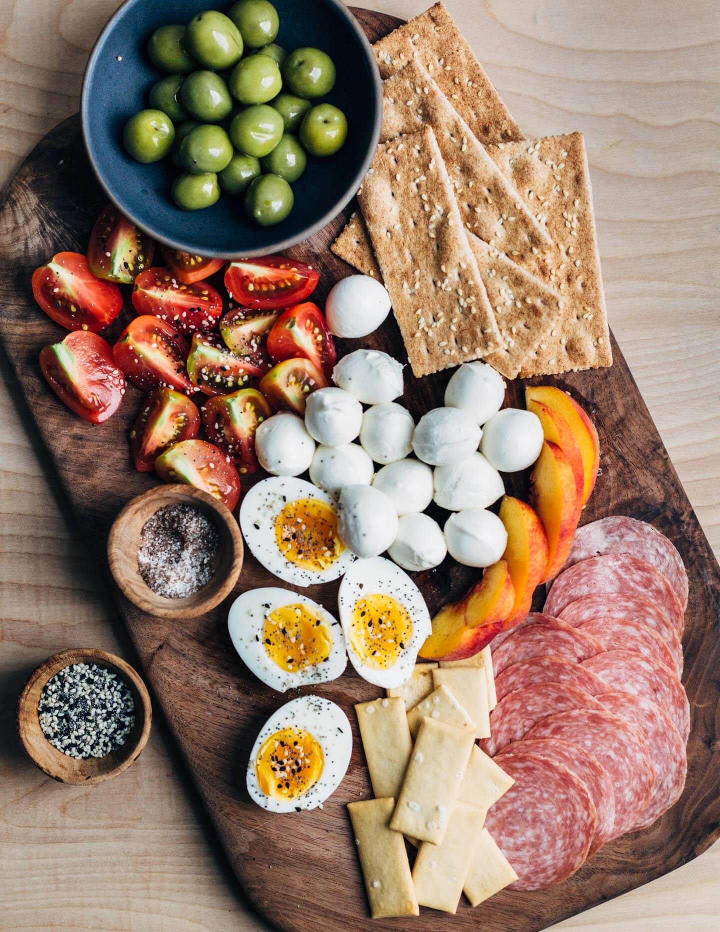 A late summer breakfast board with tomatoes, peaches, mozzarella and salami. 