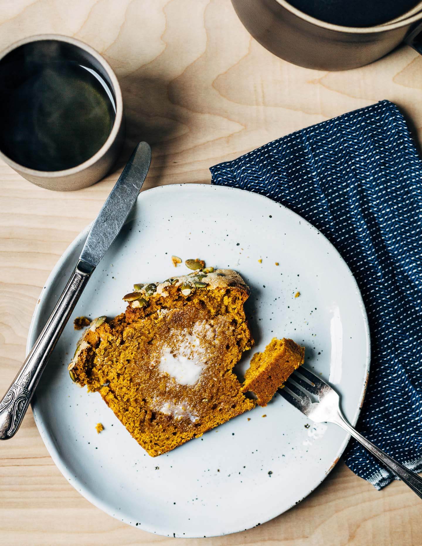 Sliced pumpkin bread with a smear of butter.