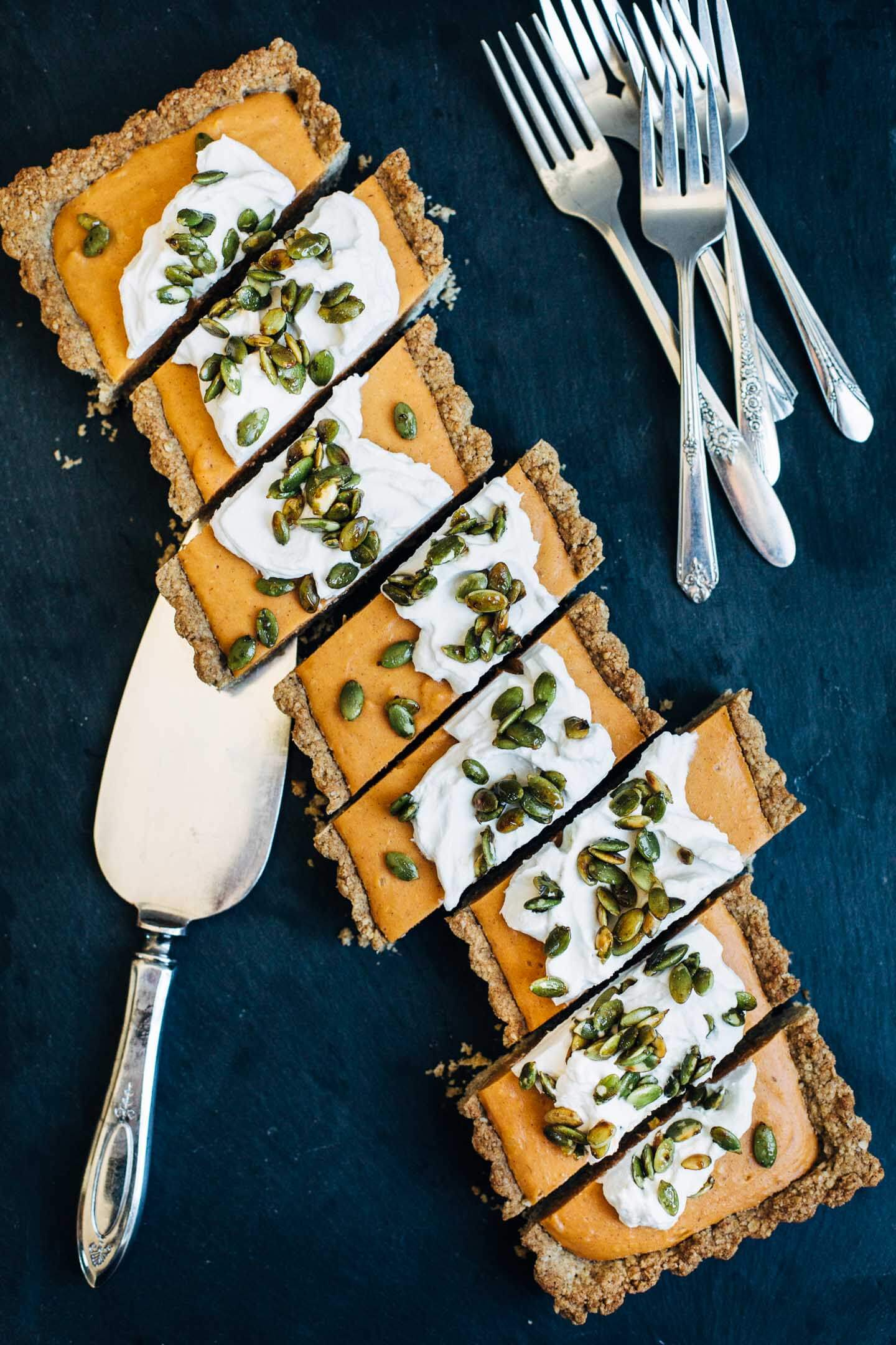 A gluten-free, vegan sweet potato tart has a silky texture with the spice and flavor of a classic sweet potato pie. It's topped with maple-sweetened coconut cream and salty-sweet toasted pepitas.