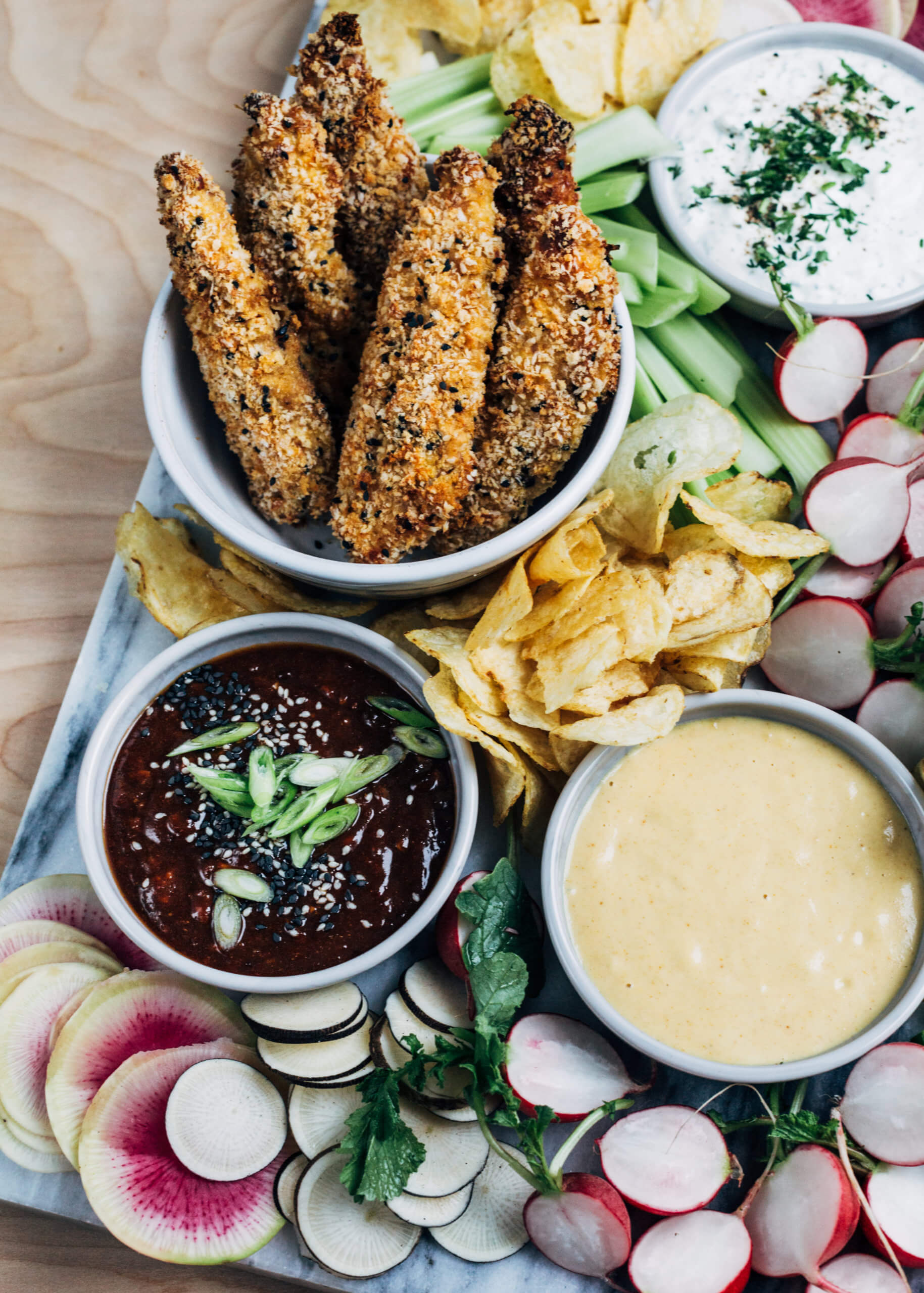 A vibrant chicken tenders board with fresh winter vegetables.