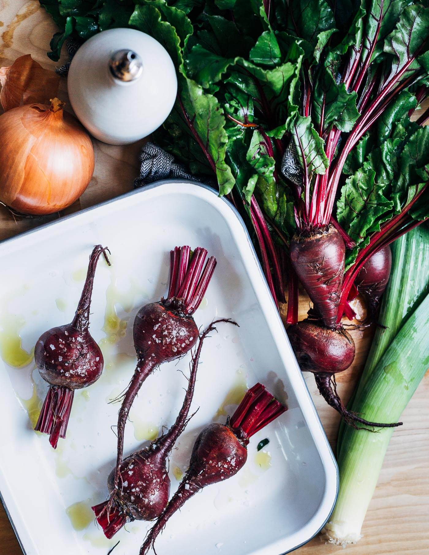 Ingredients for beet soup: beets with their greens, an onion, and a leek.