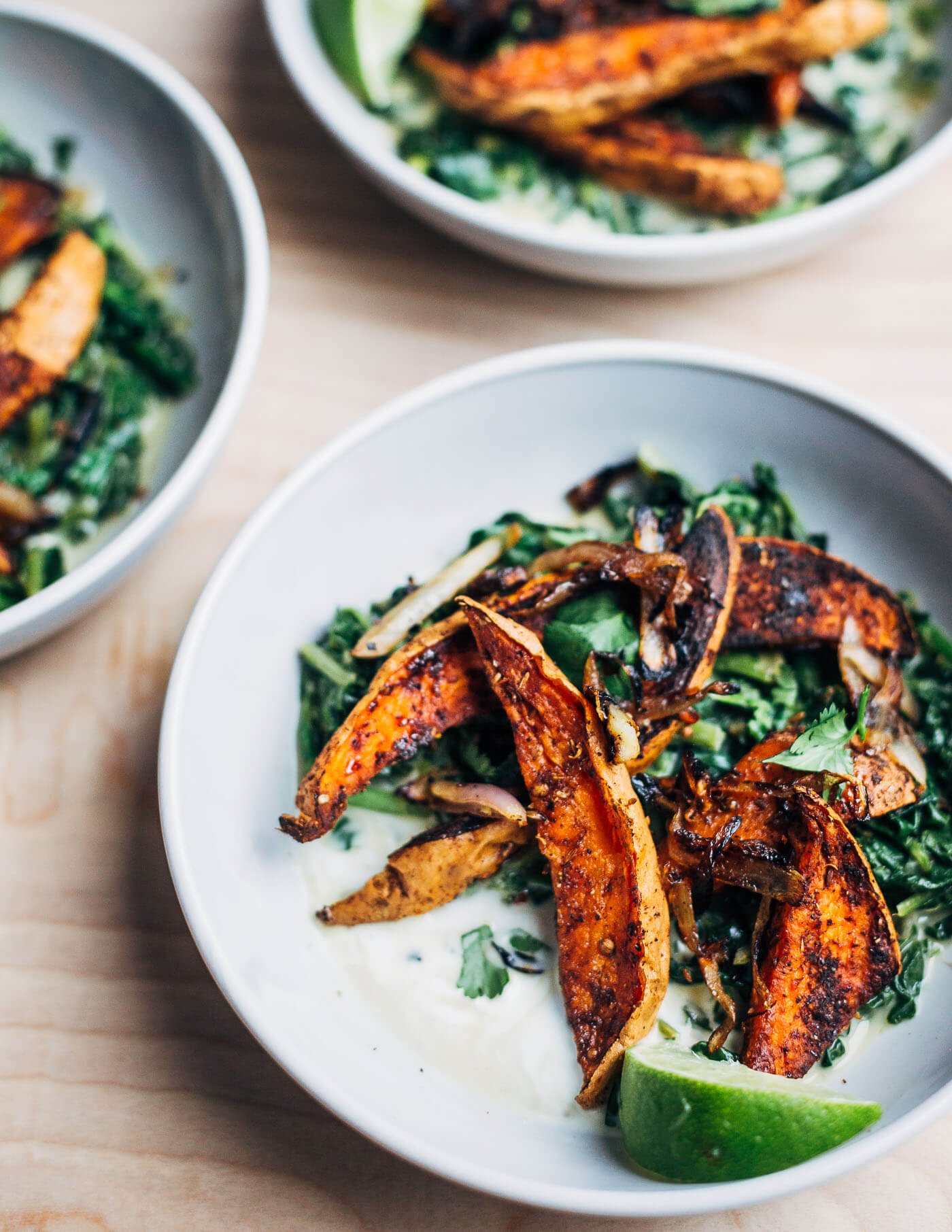 A simple approach to meltingly delicious cooked greens featuring spiced roasted sweet potato wedges and tender coconut milk braised greens with just a bit of heat.