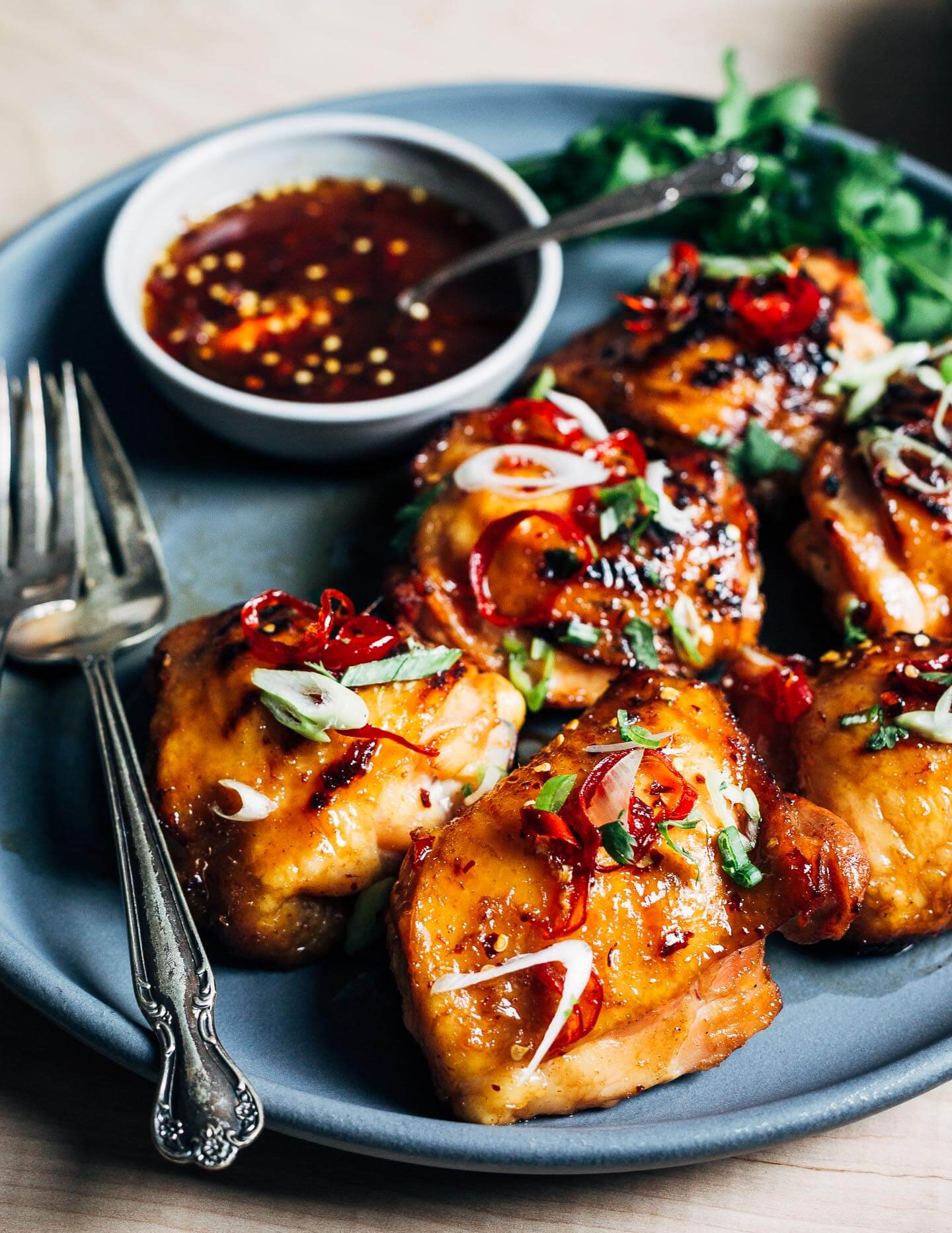 Hot honey grilled chicken thighs garnished with chilies, green onions, and cilantro. 