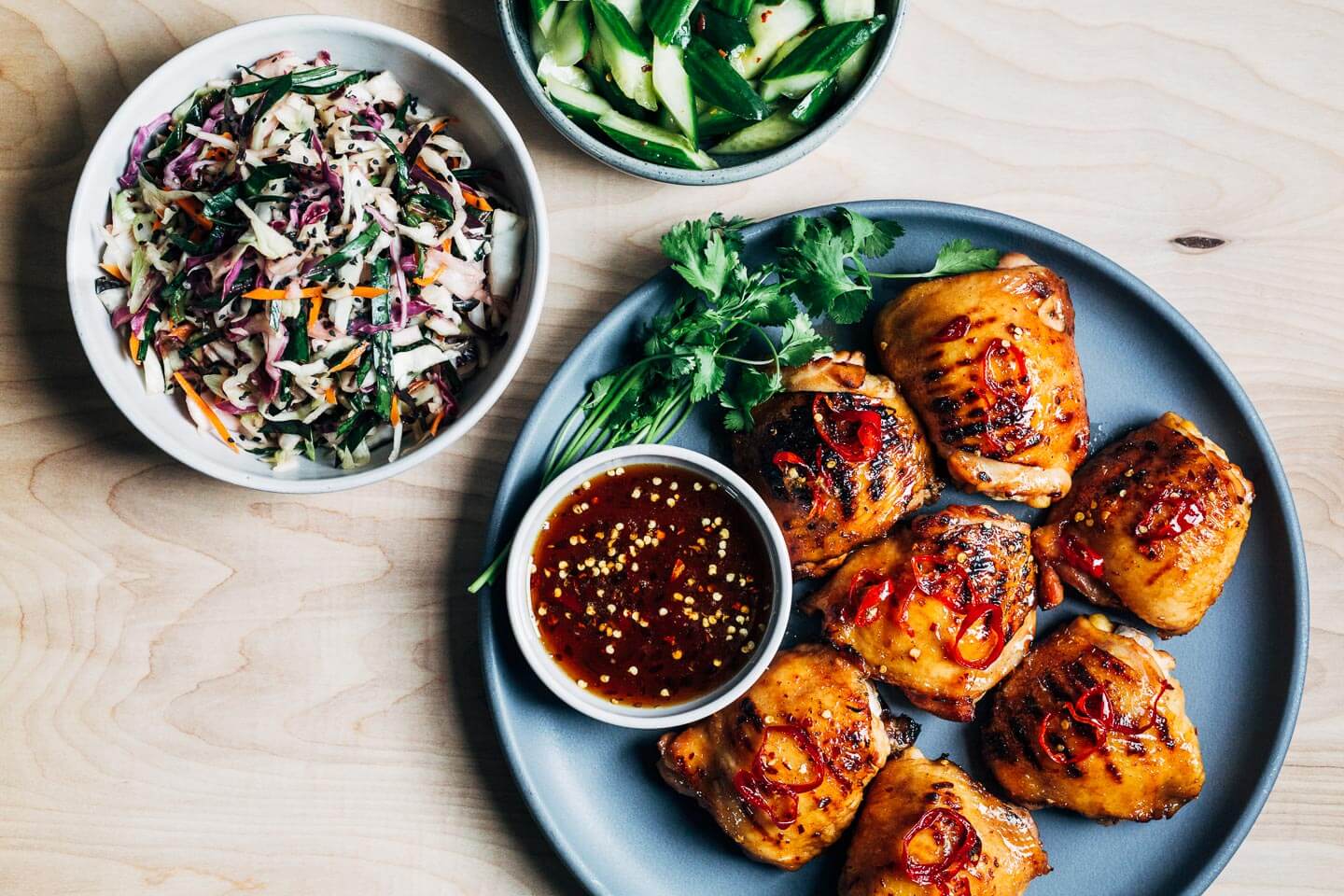 Grilled hot honey chicken thighs with a vibrants slaw and spicy cucumber salad. 