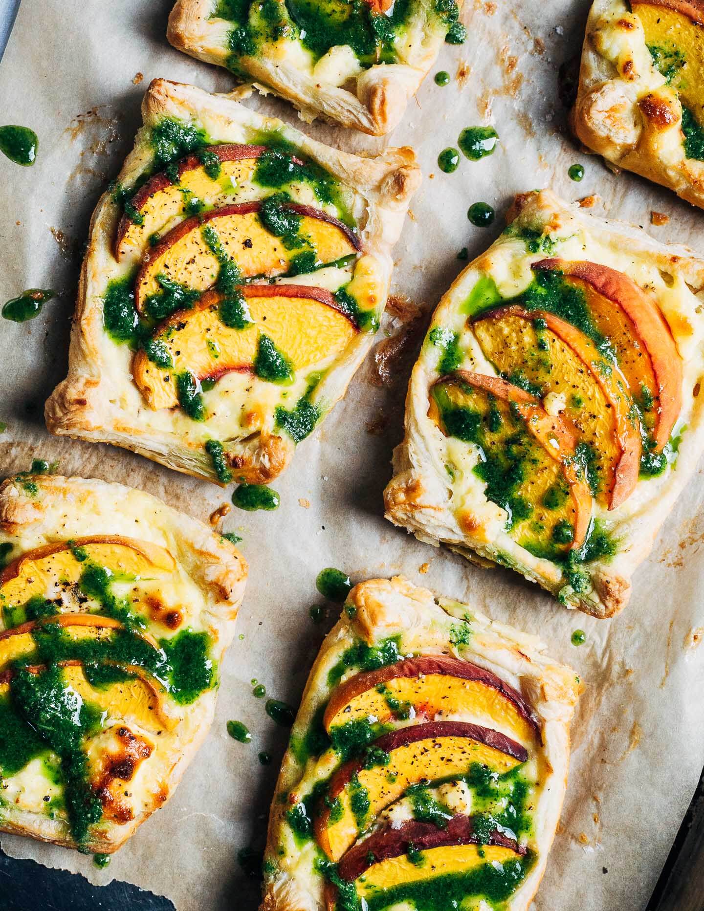 These little savory peach and ricotta tarts are made with flaky puff pastry and drizzled with herbaceous basil olive oil. They come together quickly and capture the flavors of peak summer perfectly.