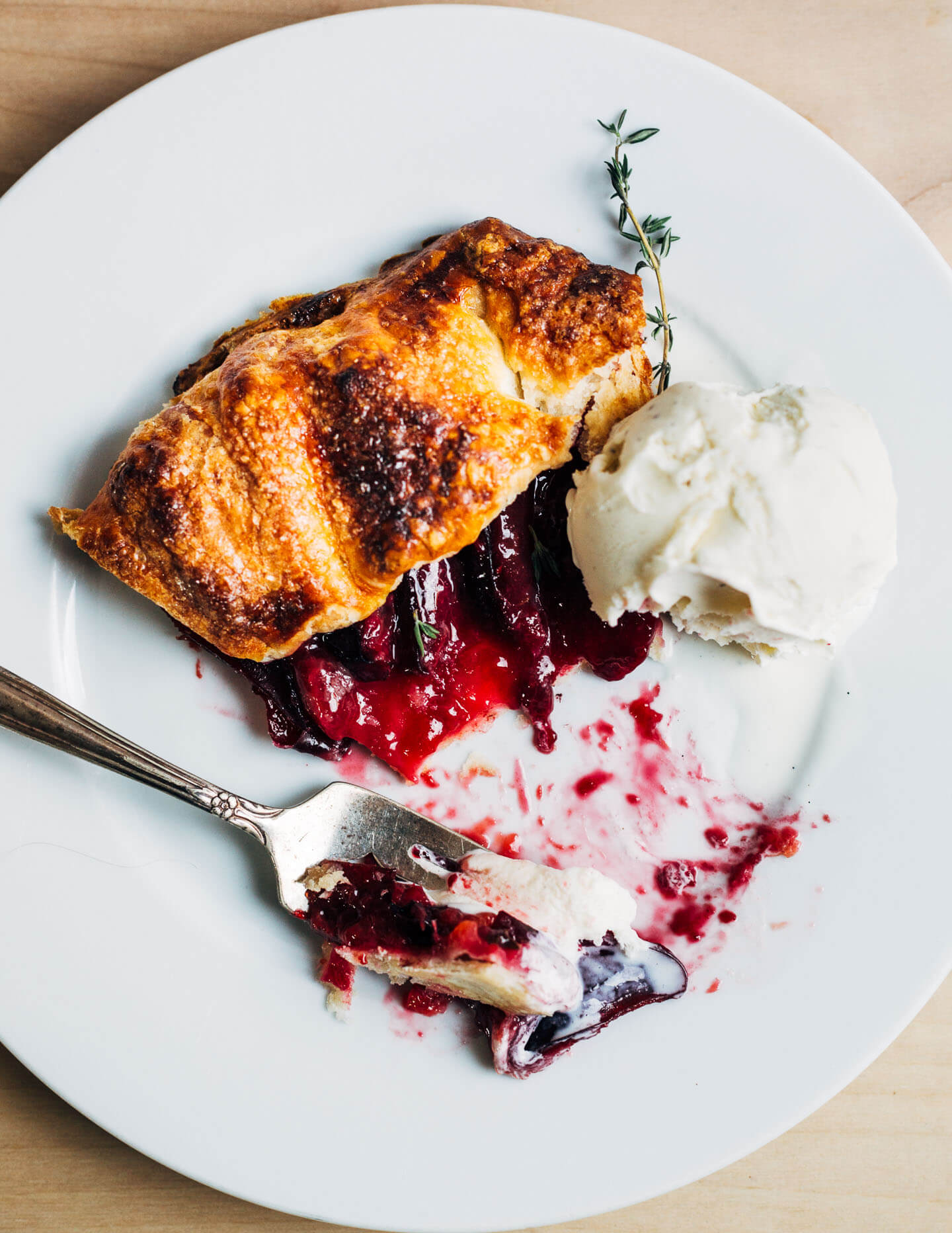 A slice of plum galette served with fresh thyme and vanilla ice cream.