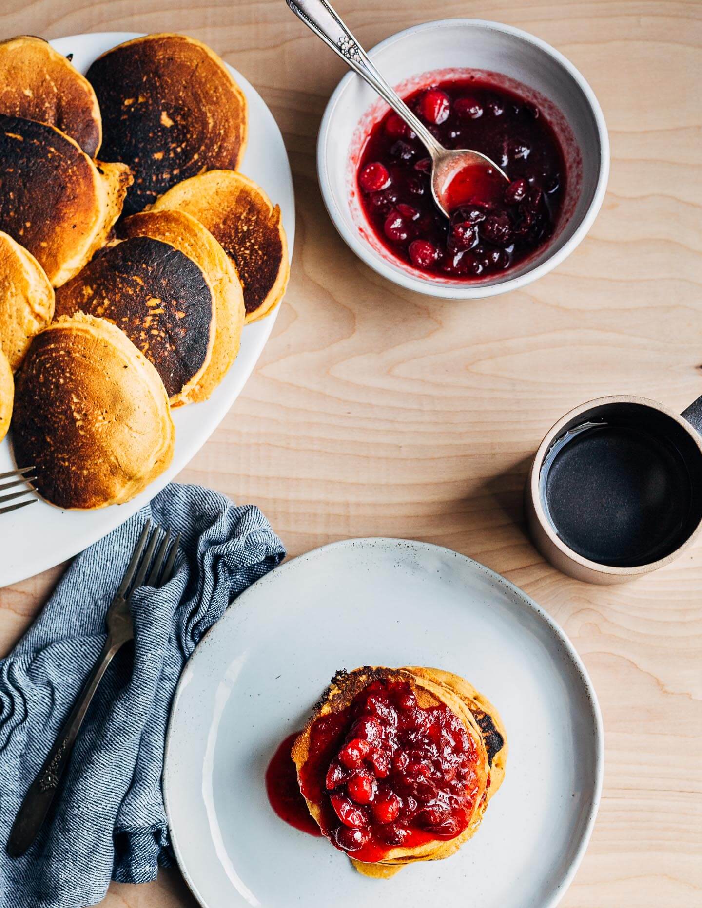 Use up your leftover pumpkin puree and cranberry sauce with this simple recipe for vegan pumpkin pancakes with cranberry maple syrup.