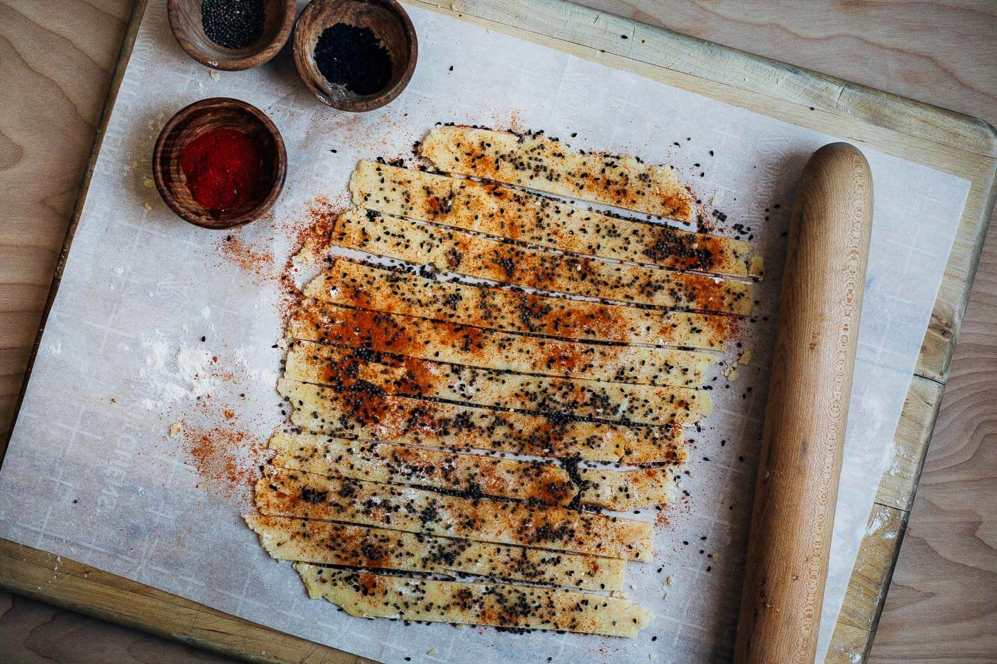 Cutting nigella and mustard seed cheese straws dusted with paprika. 