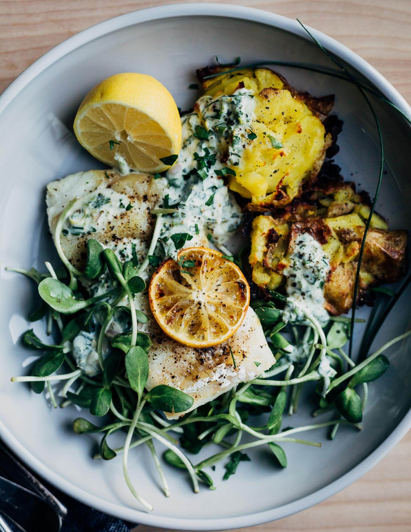 An ode to early spring, this weeknight dinner recipe features crispy smashed potatoes, flaky cod, and a dollop of punchy wild chive crème fraîche.