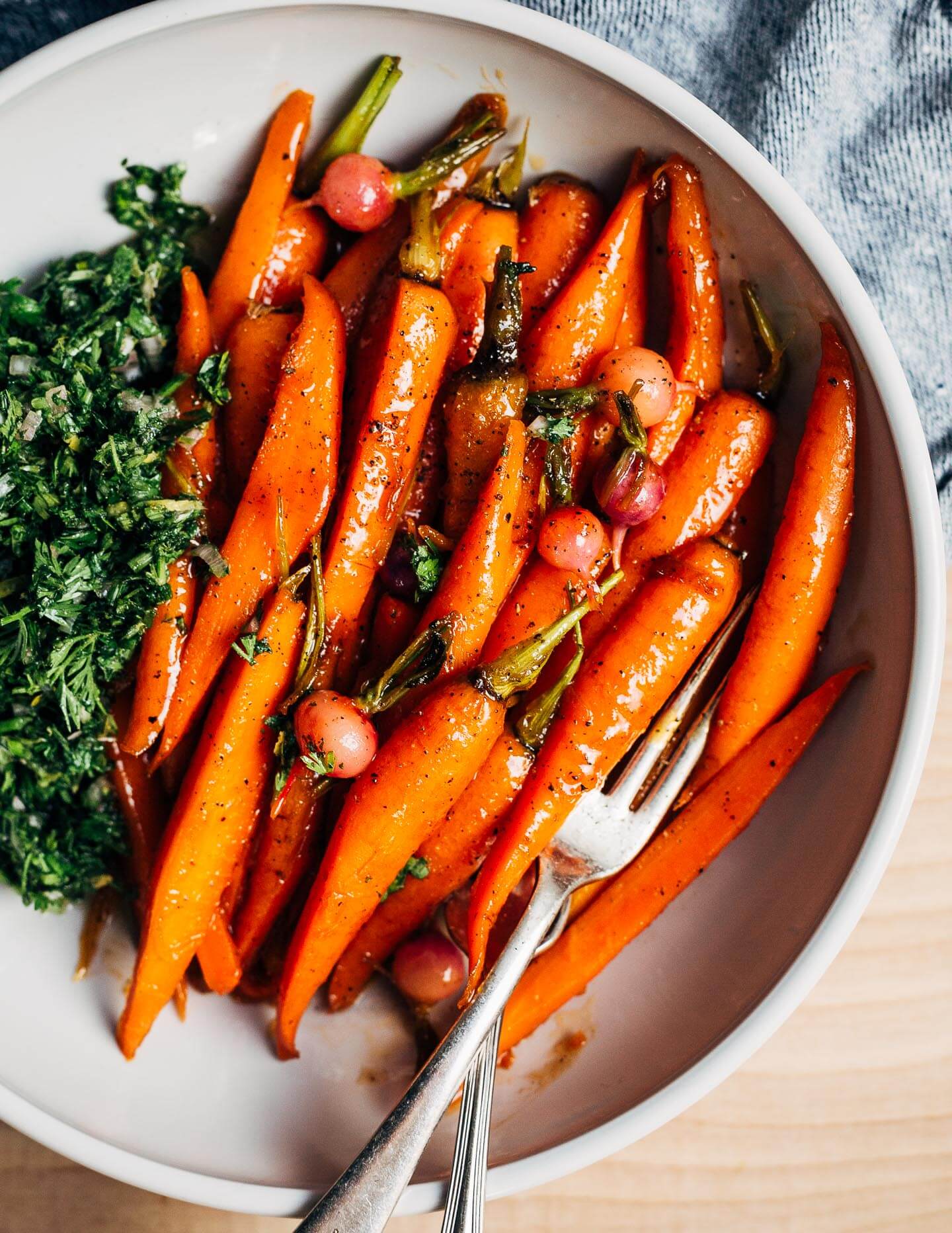 These springy glazed carrots are delightfully buttery and light with a vegetable broth-based glaze and are served alongside a bright carrot top chimichurri.