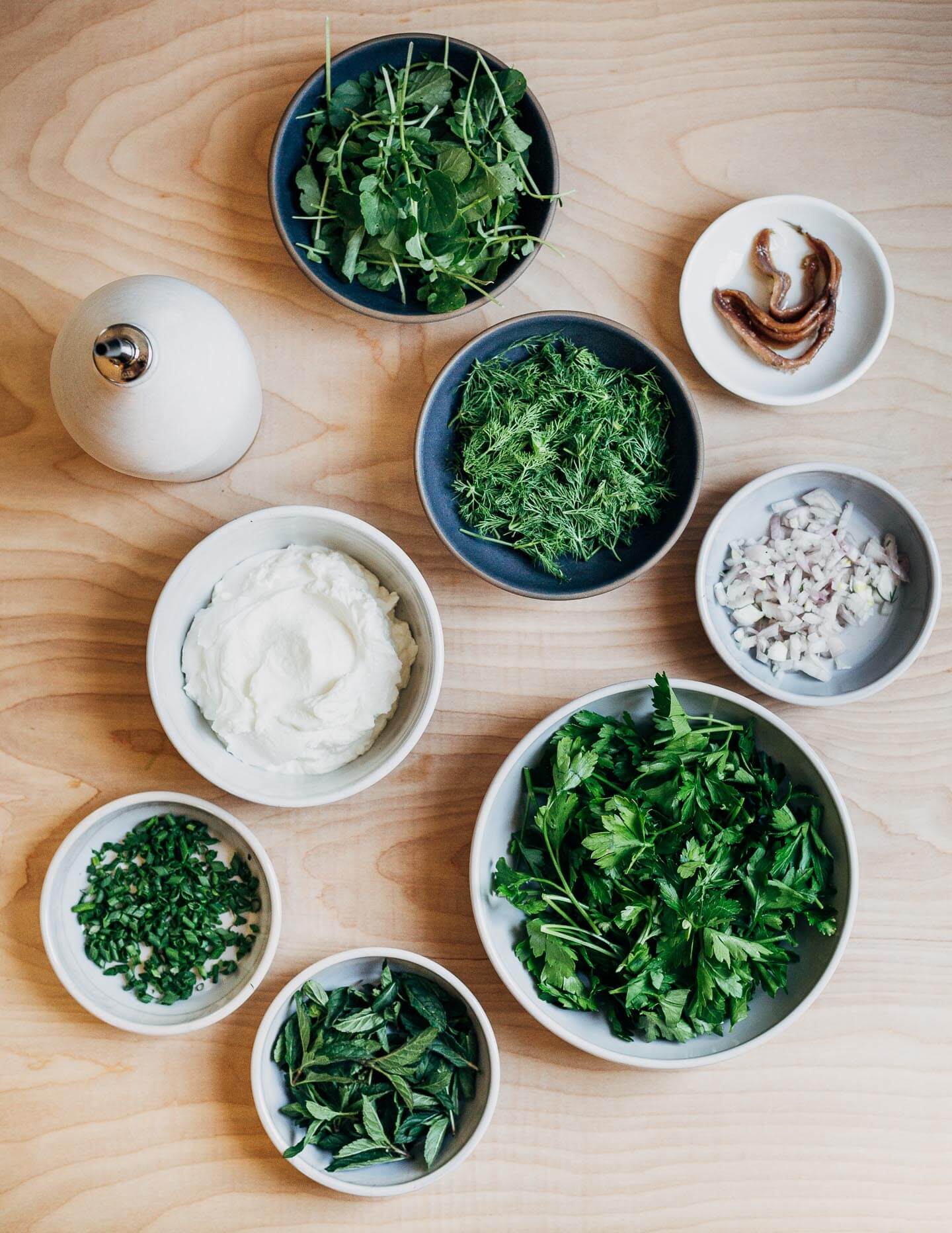 Ingredients for green goddess dip: watercress, parsley, dill, mint, chives, shallots, anchovies, yogurt, and olive oil.