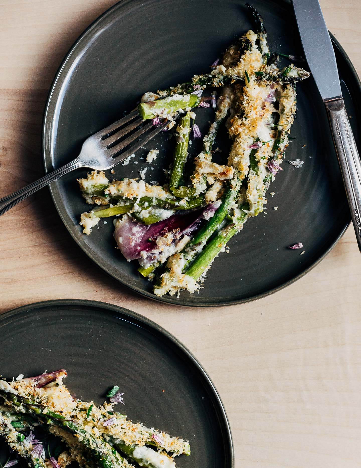 Two dark green plates with servings of asparagus gratin. 