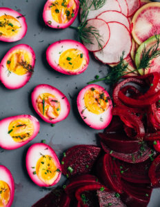 A gray platter with pink eggs and pickled beets.